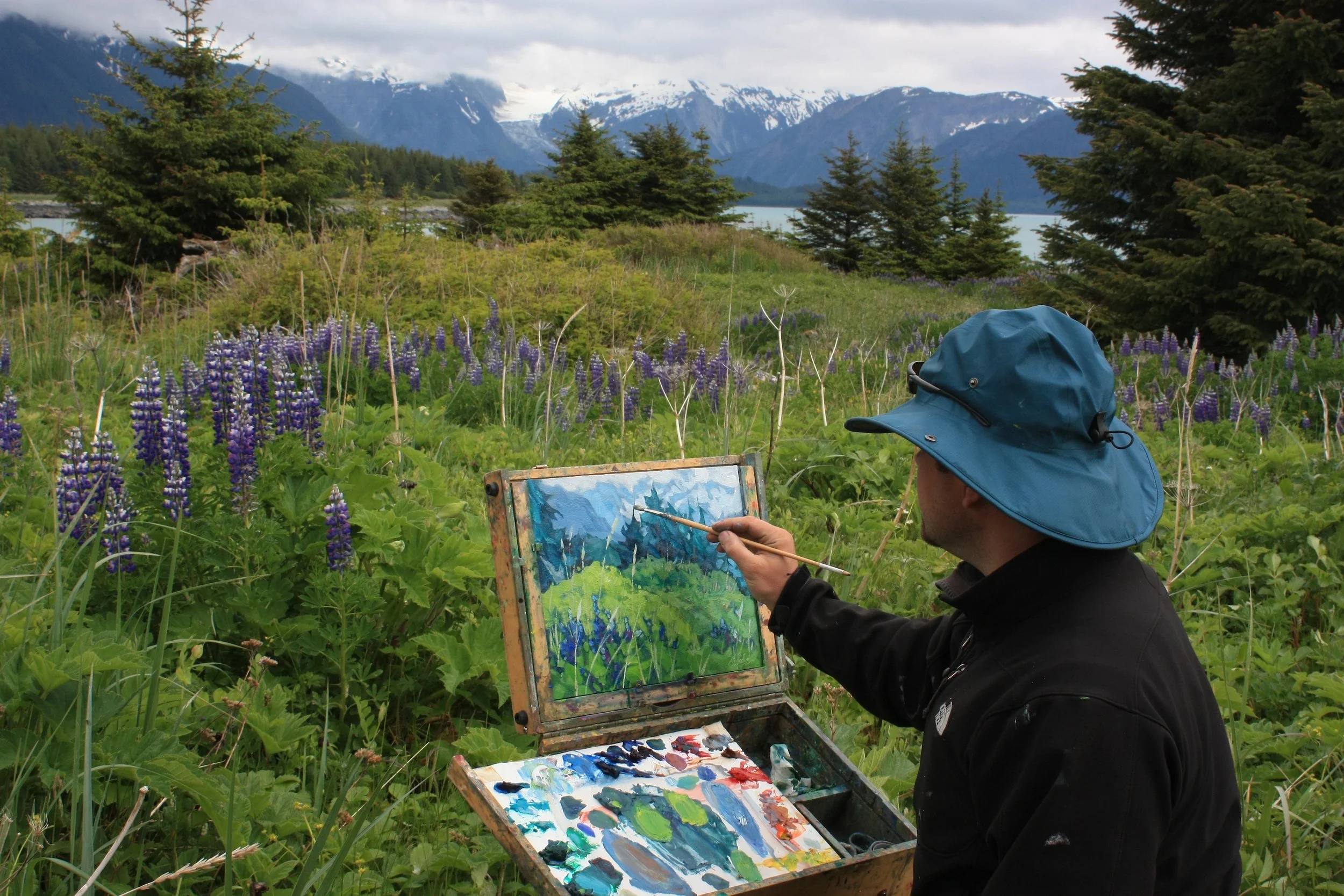 Artist Dominik Modlinski creating a plein air landscape painting in the remote mountains of Alaska.