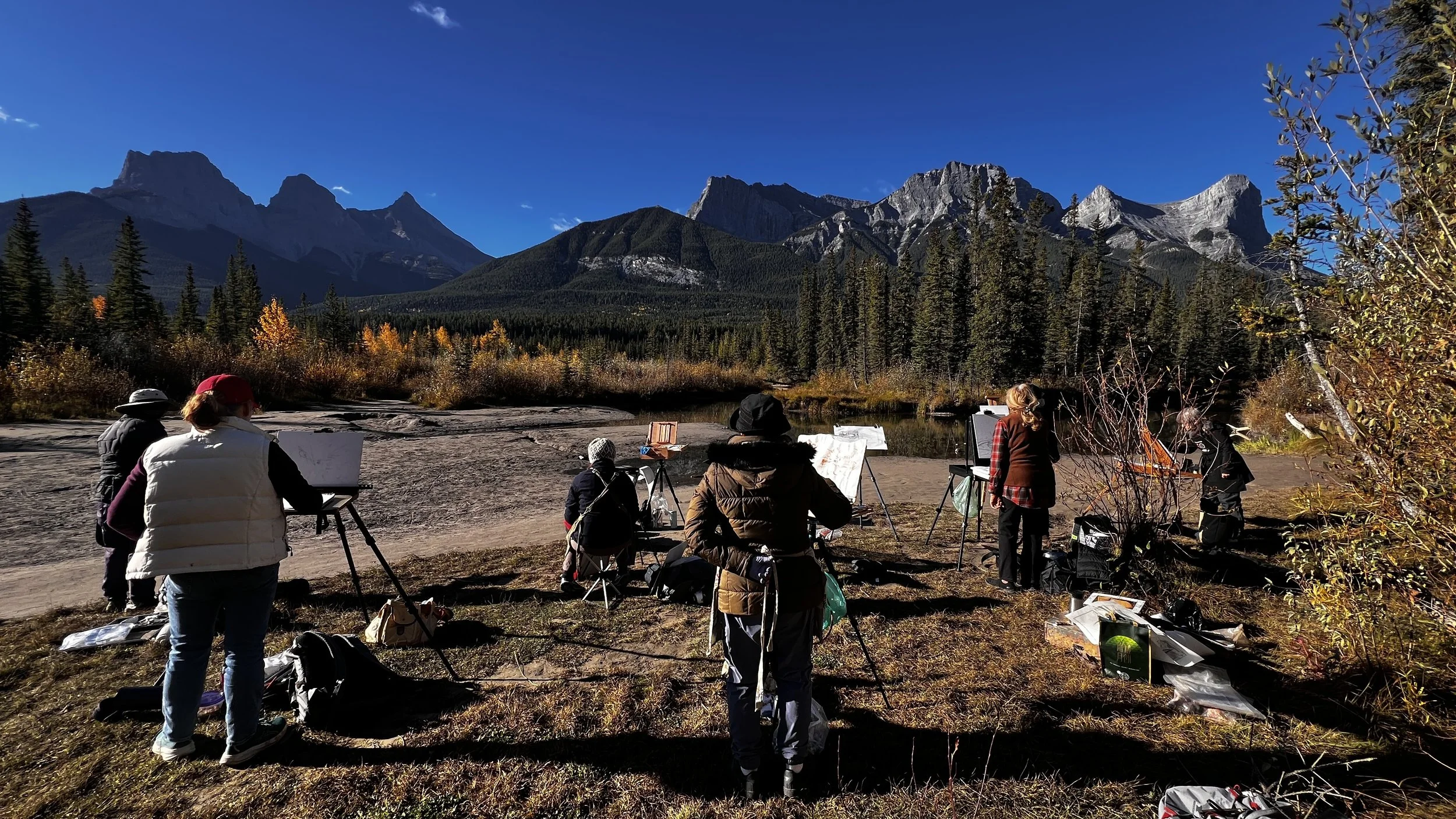 Plein air painting workshop in the Canadian Rockies, with artists painting dramatic mountain landscapes outdoors.