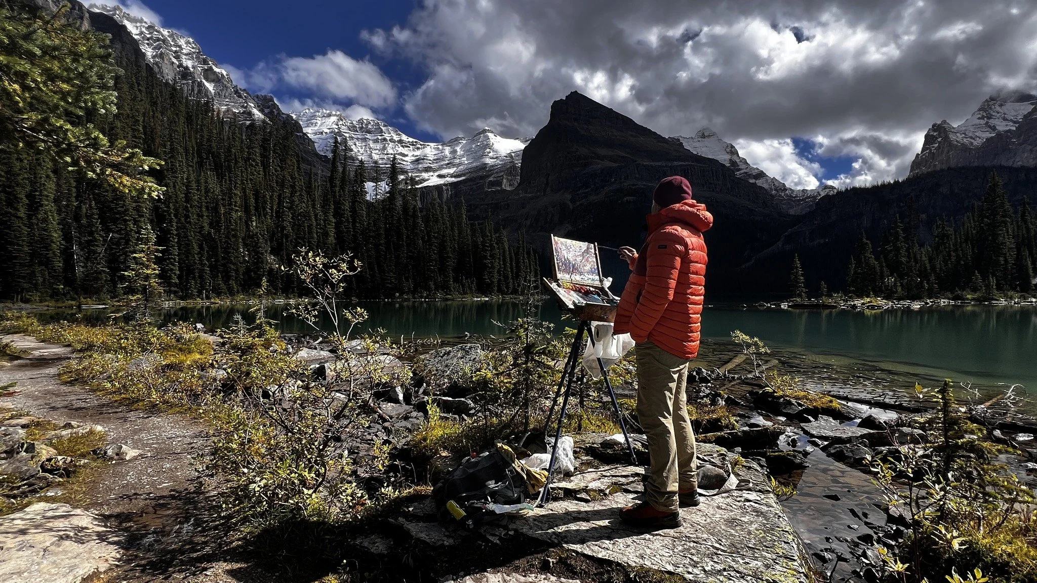 Artist painting en plein air beside Lake O’Hara in Yoho National Park, capturing alpine reflections and mountain light.