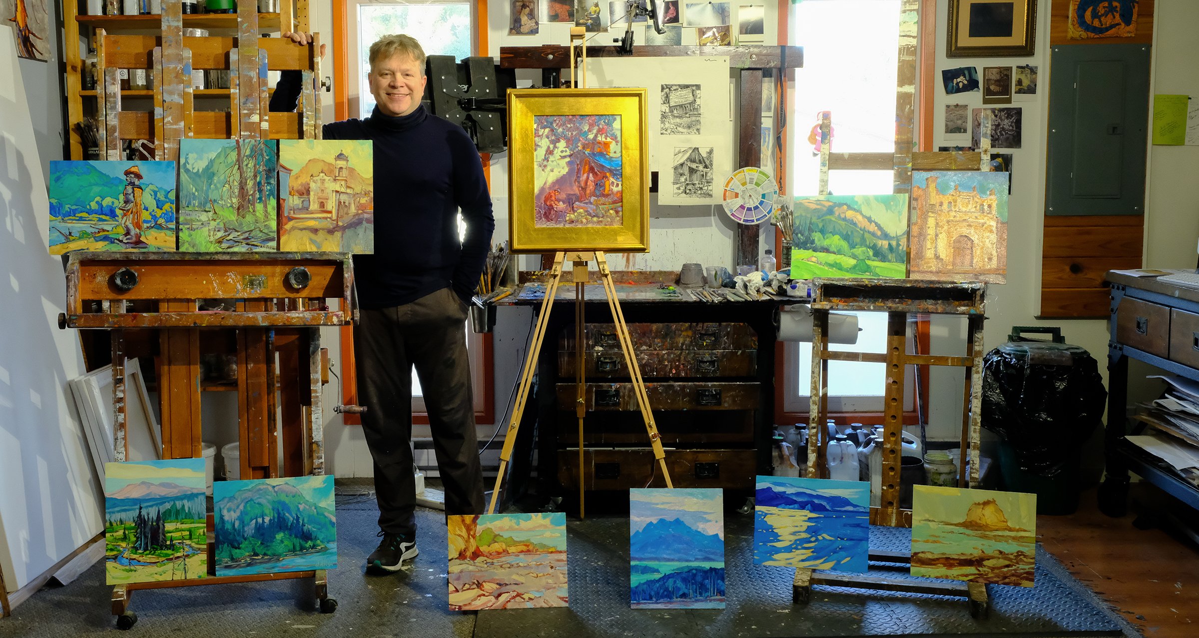 Plein air landscape painter Dominik Modlinski in his studio surrounded by original outdoor paintings created on location