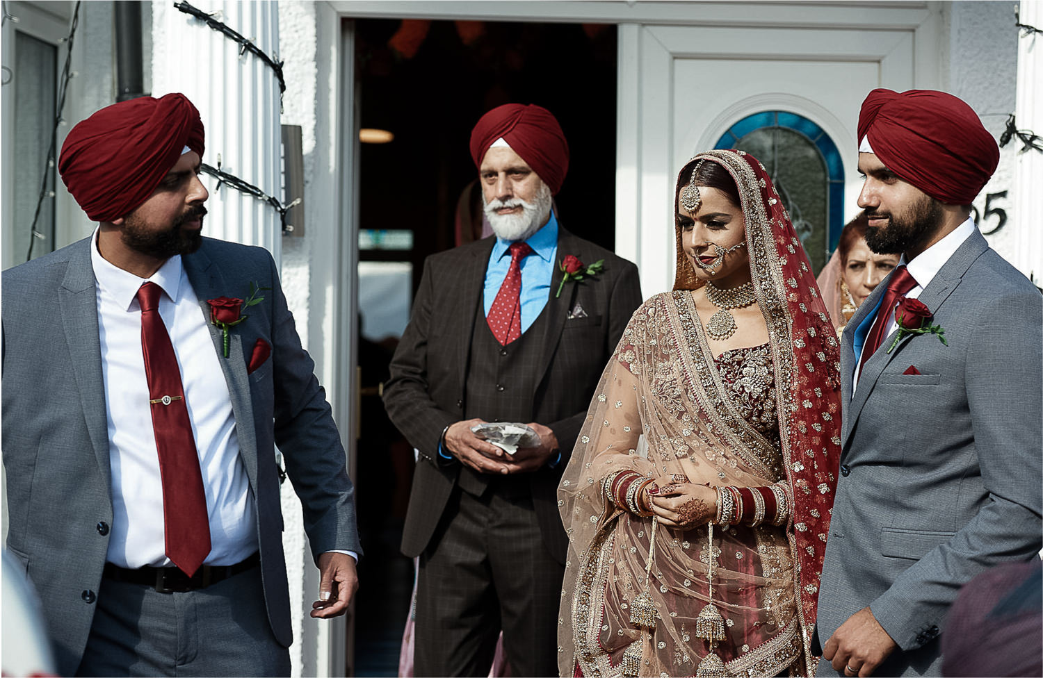 Father and brothers leading indian bride out of her house in the morning