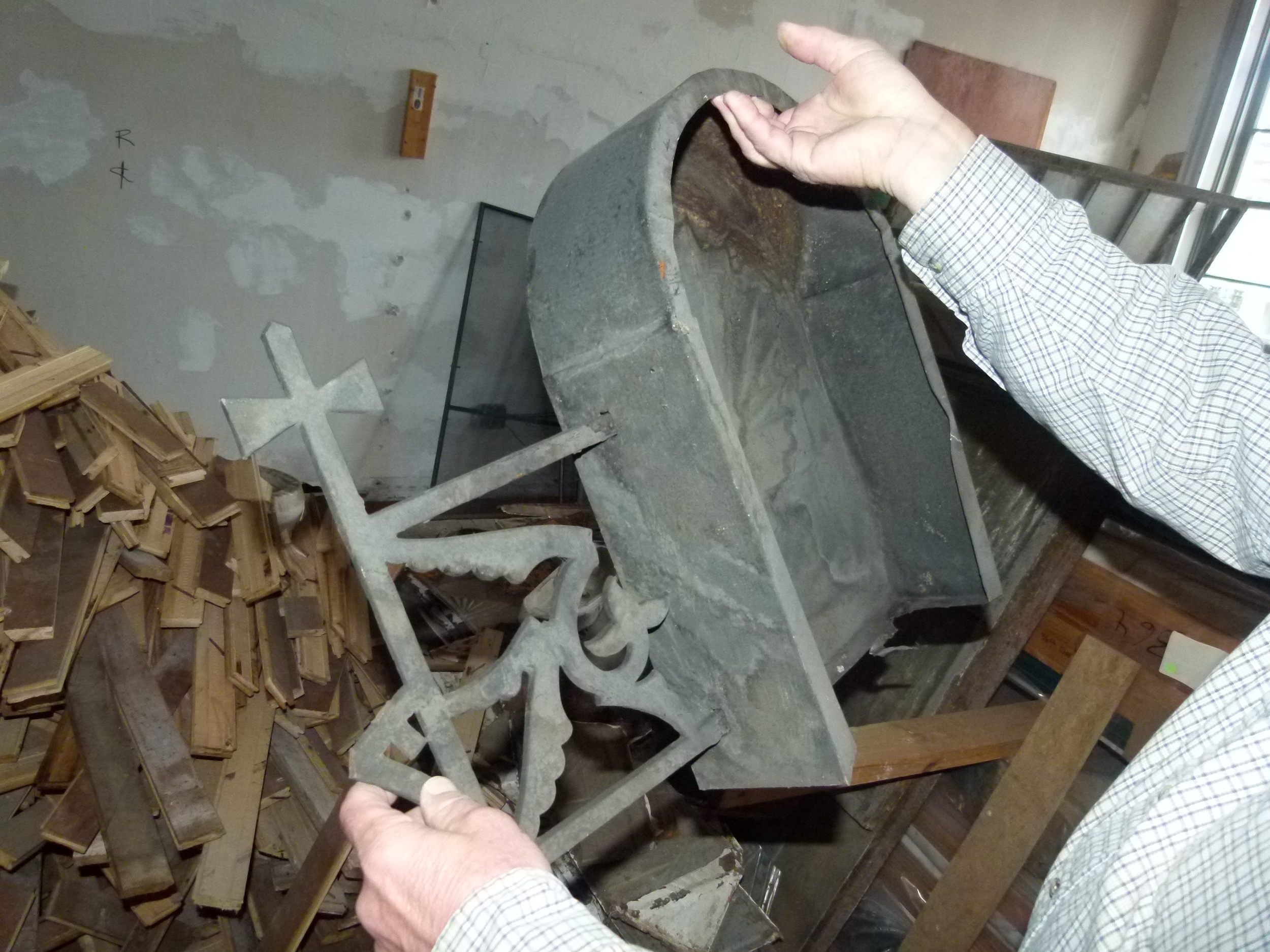 The contractor holds up the decorative metal fragment found in the 19th century building