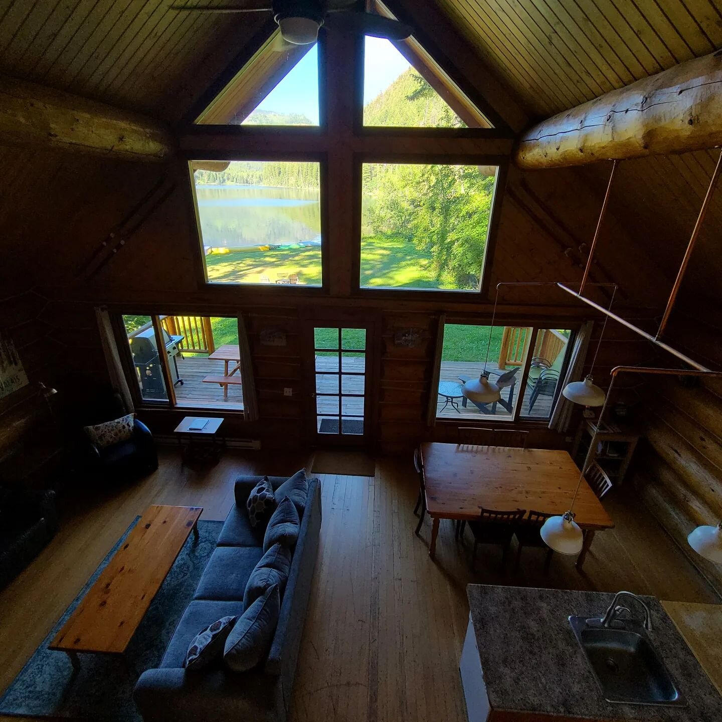 How about a tour? This view from the upstairs balcony gives you a sneak peak of the expansive lawn leading to the lake. Check out the custom copper light fixture made by host Rod! 
#chaletnufer #chaletstyle #cabin #cabinlife #rentalproperty #caribouc