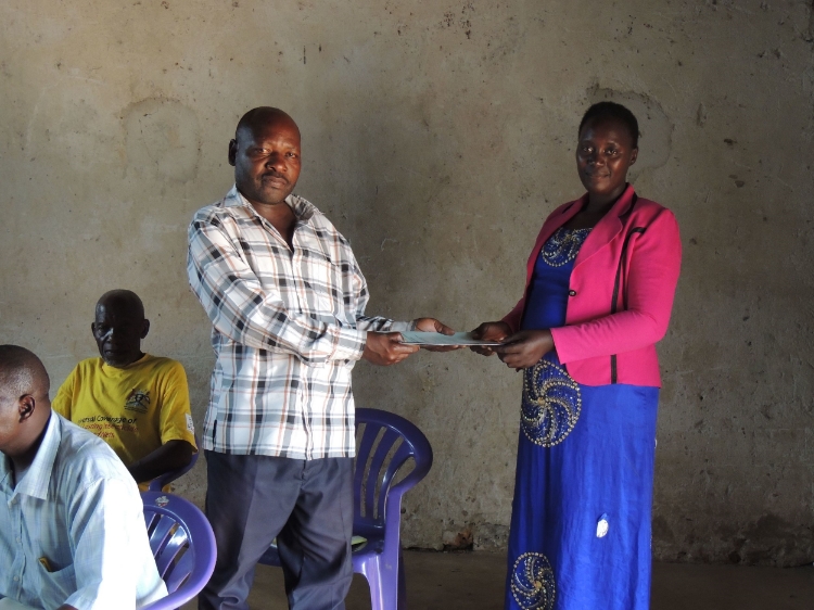 Photo: Peninah handing over the Health and Livelihood survey to the Chairperson of Nalutuntu Sub-County, Kamulegeya Peterson
