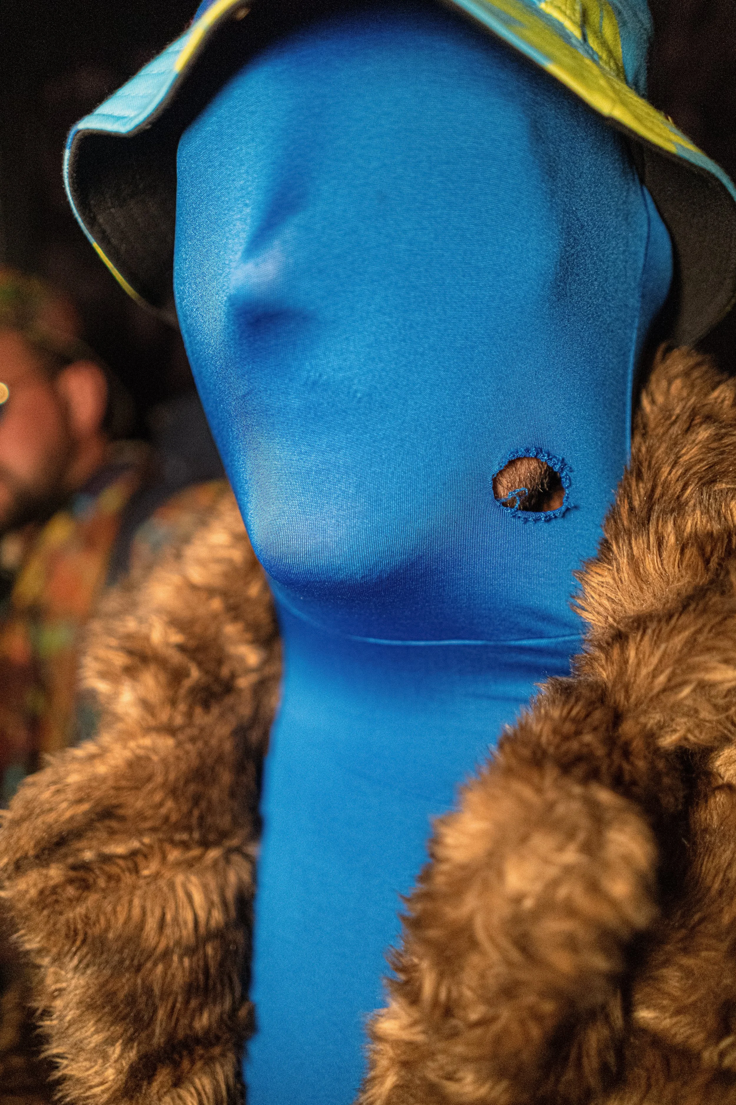 A Glastonbury festivalgoer wears a full blue face covering, a hat and a furry coat.