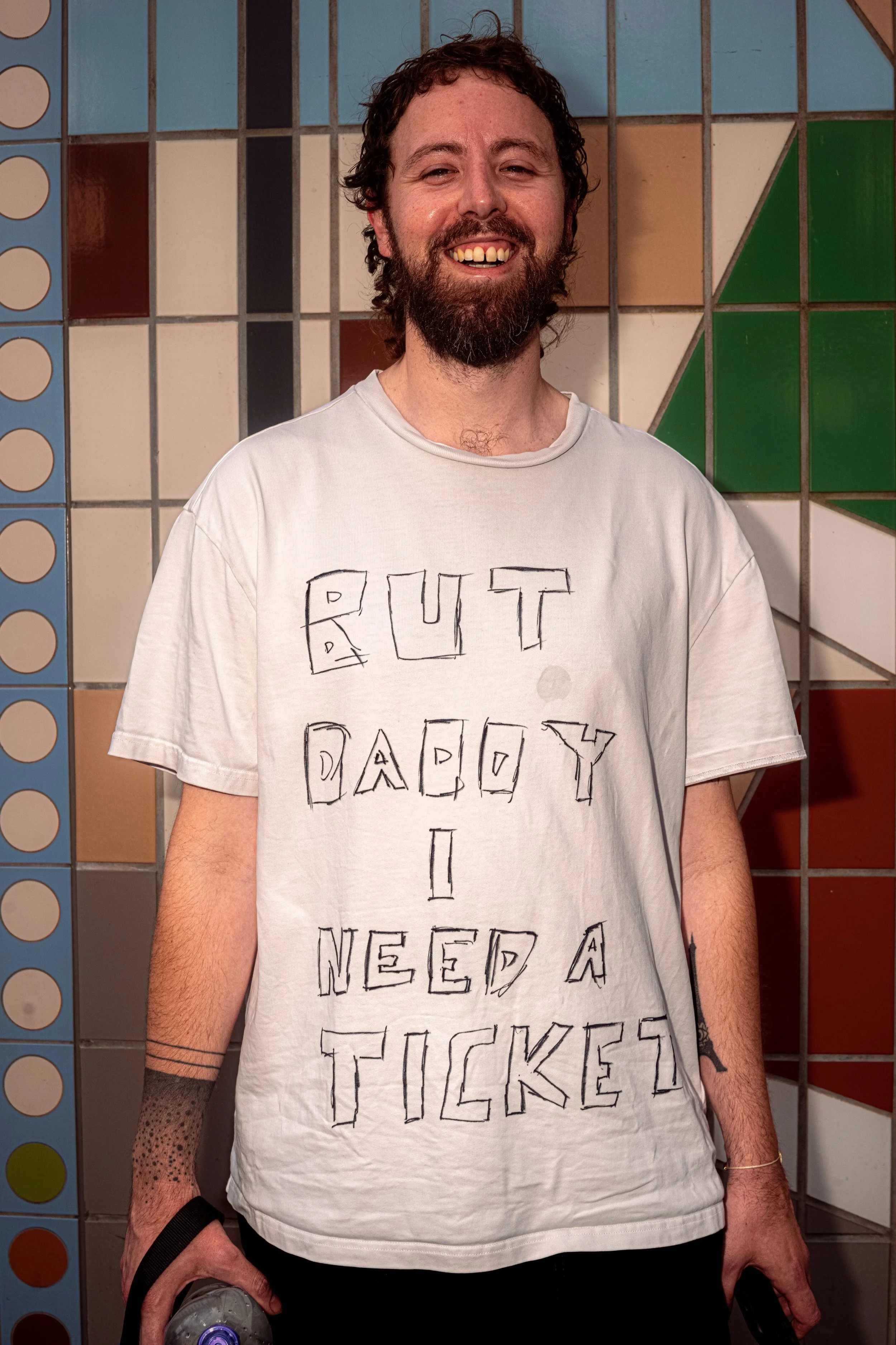 A bearded Taylor Swift fan wears a handwritten T-shirt asking for a ticket.