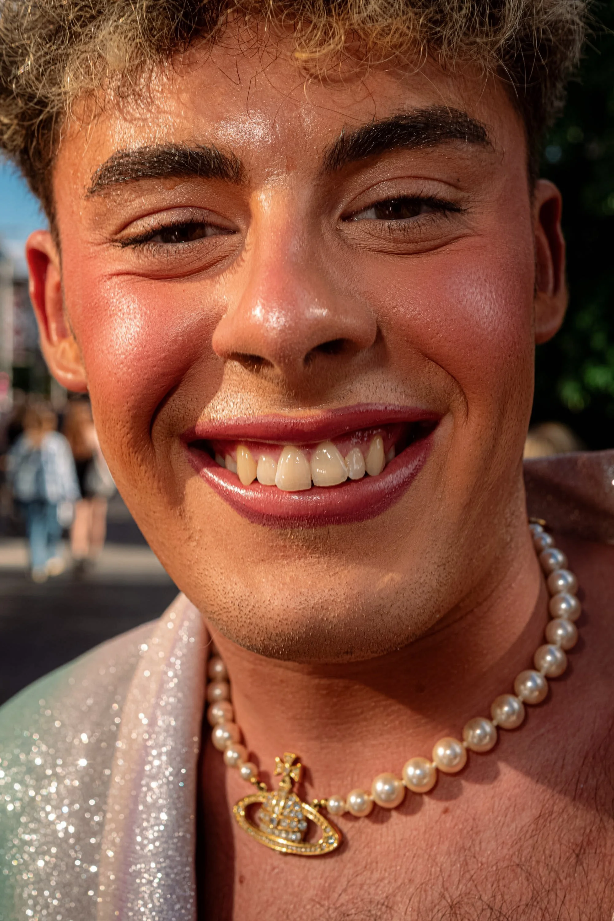 Close-up of a smiling Taylor Swift fan wearing pink eye makeup, red lipstick and a pearl necklace.