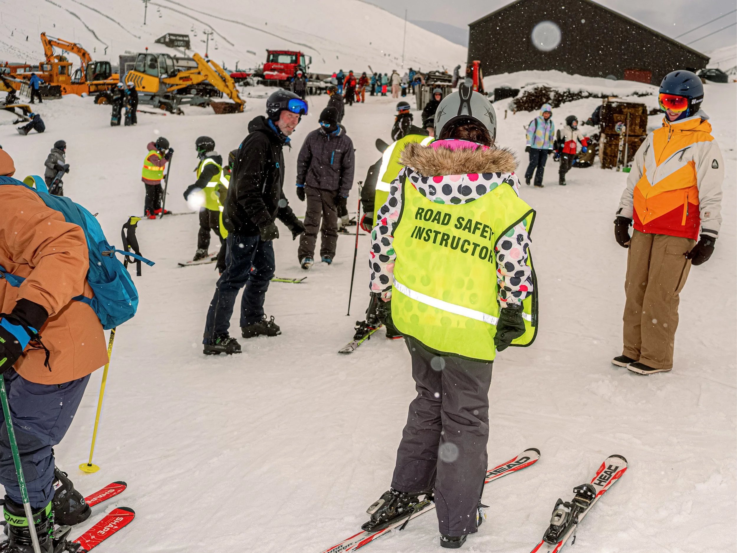 A young skier wears a fluorescent “Road Safety Heroes” vest on a busy snowy slope, from Weather Permitting.