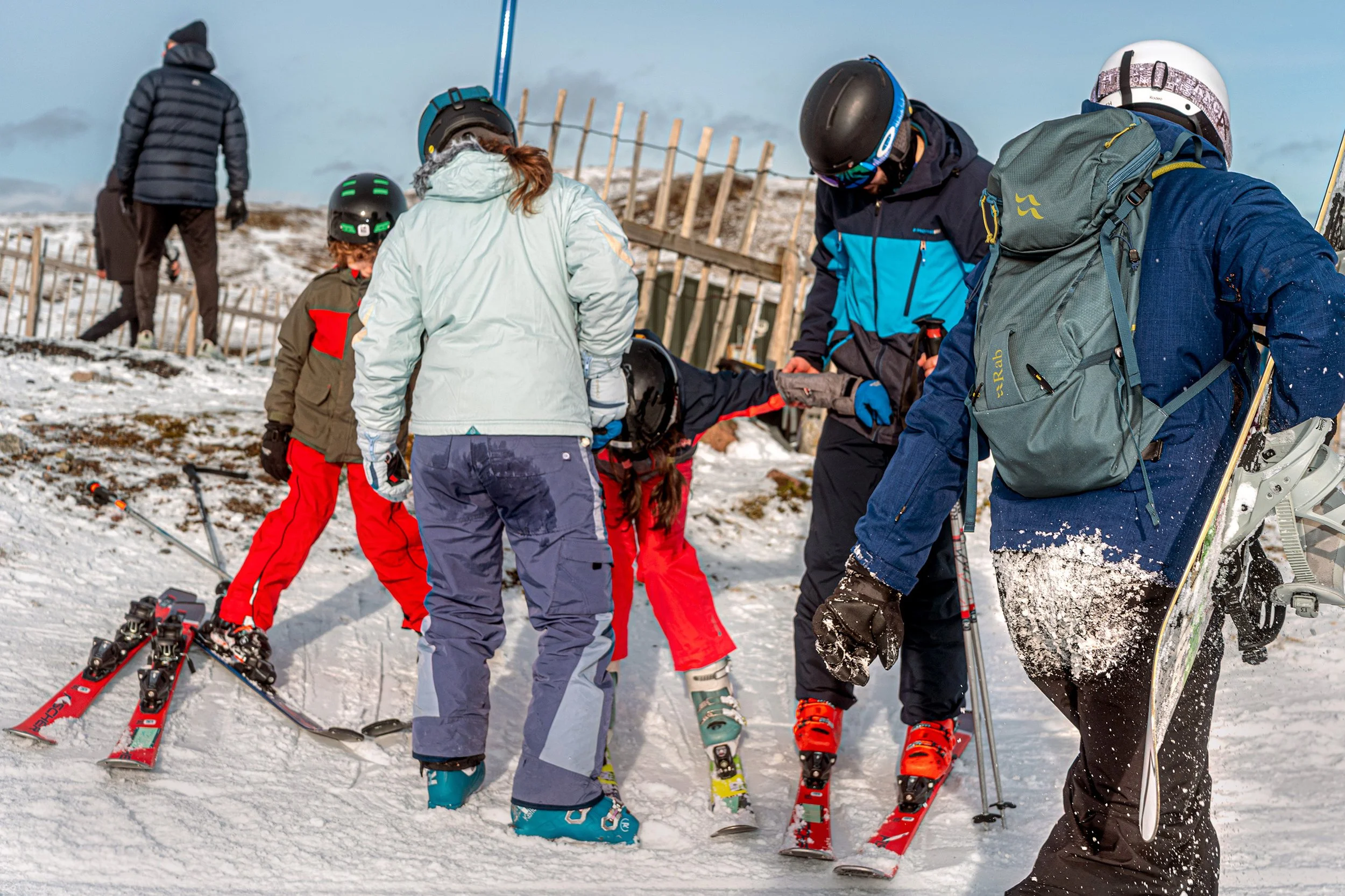 A group of skiers, including children, set off together on a sunny slope.