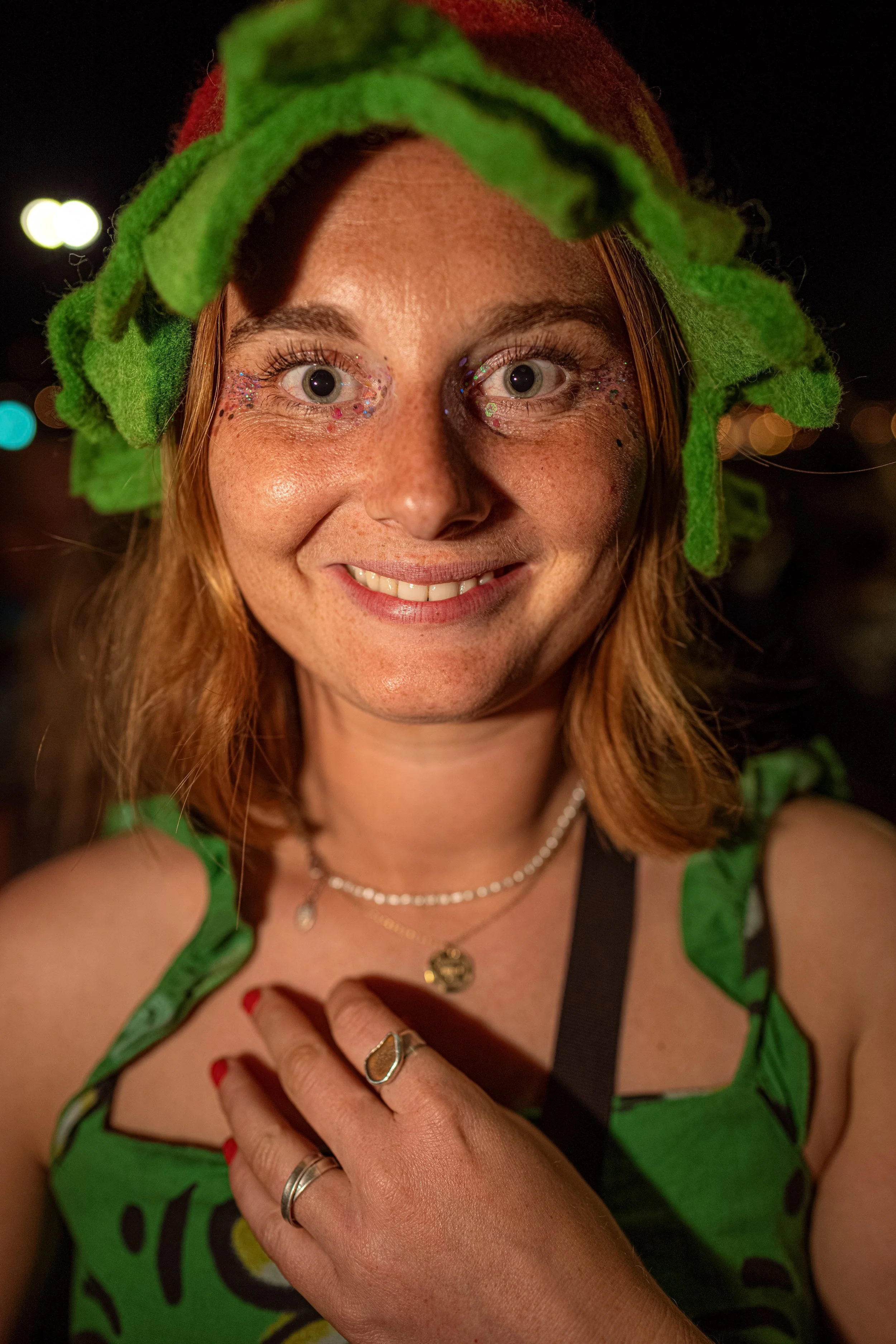 A smiling Glastonbury festivalgoer wears a green leafy headpiece and matching outfit.