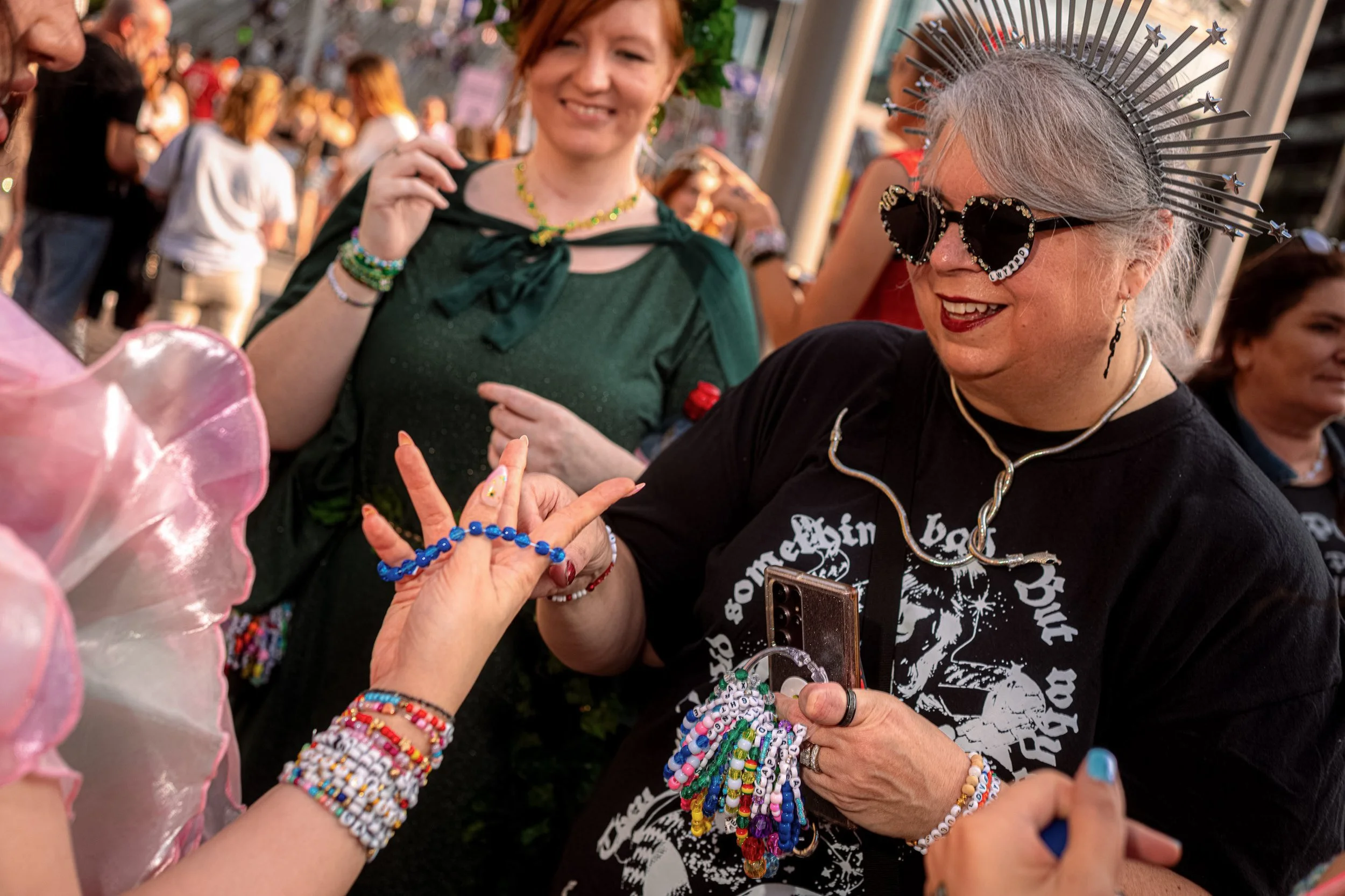 A Taylor Swift fan wearing a spiked silver headpiece and black sunglasses exchanges friendship bracelets.