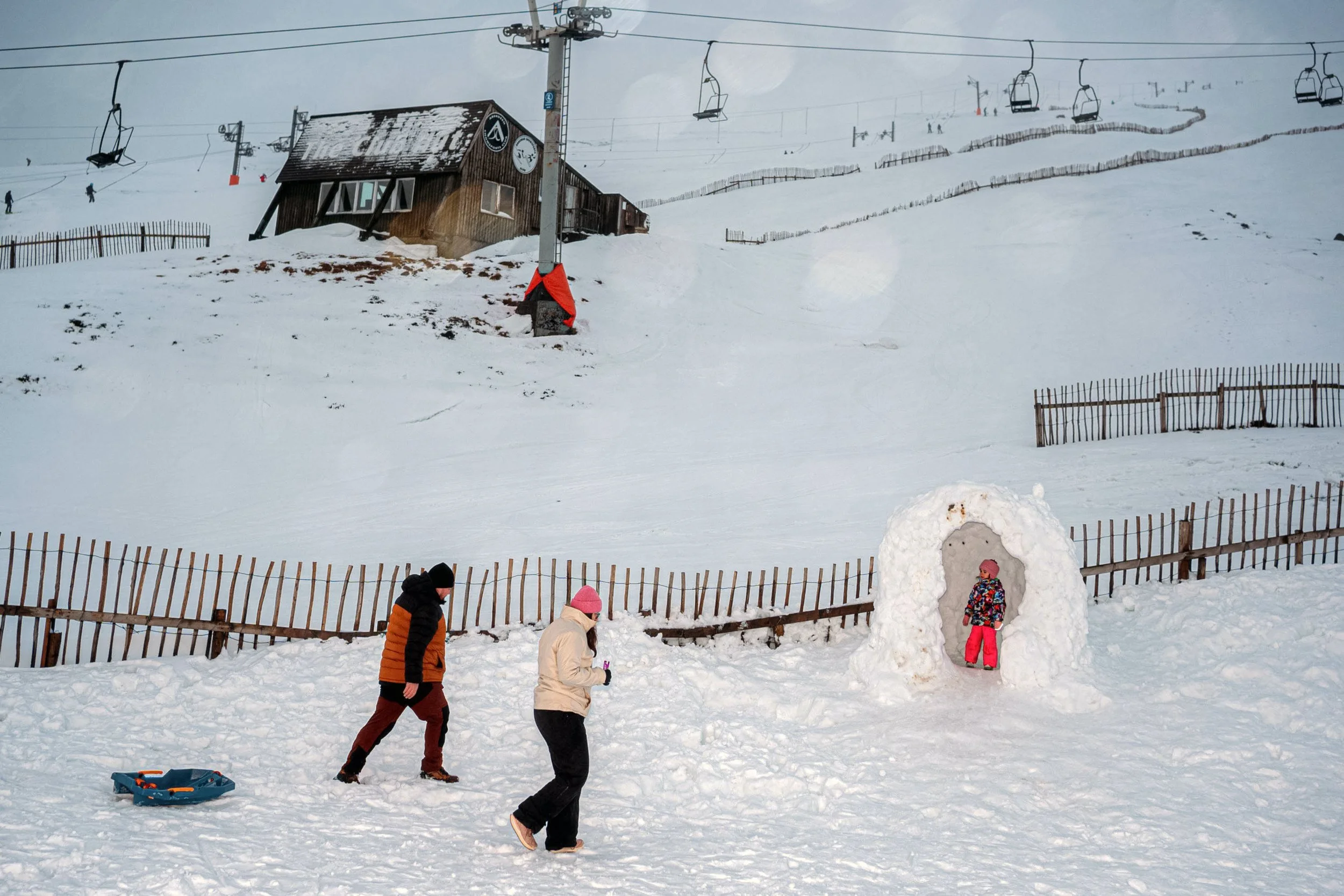 Visitors stand near a snow arch below a ski lift on a Scottish mountainside, from Weather Permitting.
