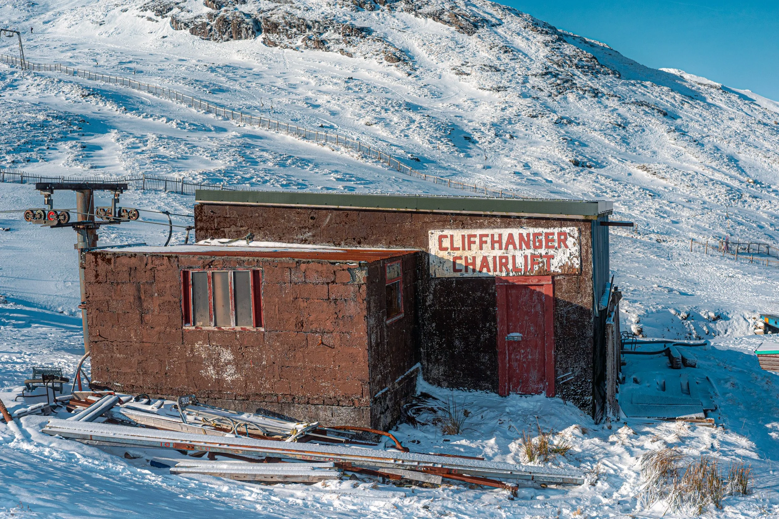 The snow-covered Cliffhanger Chairlift hut on a bright winter hillside.