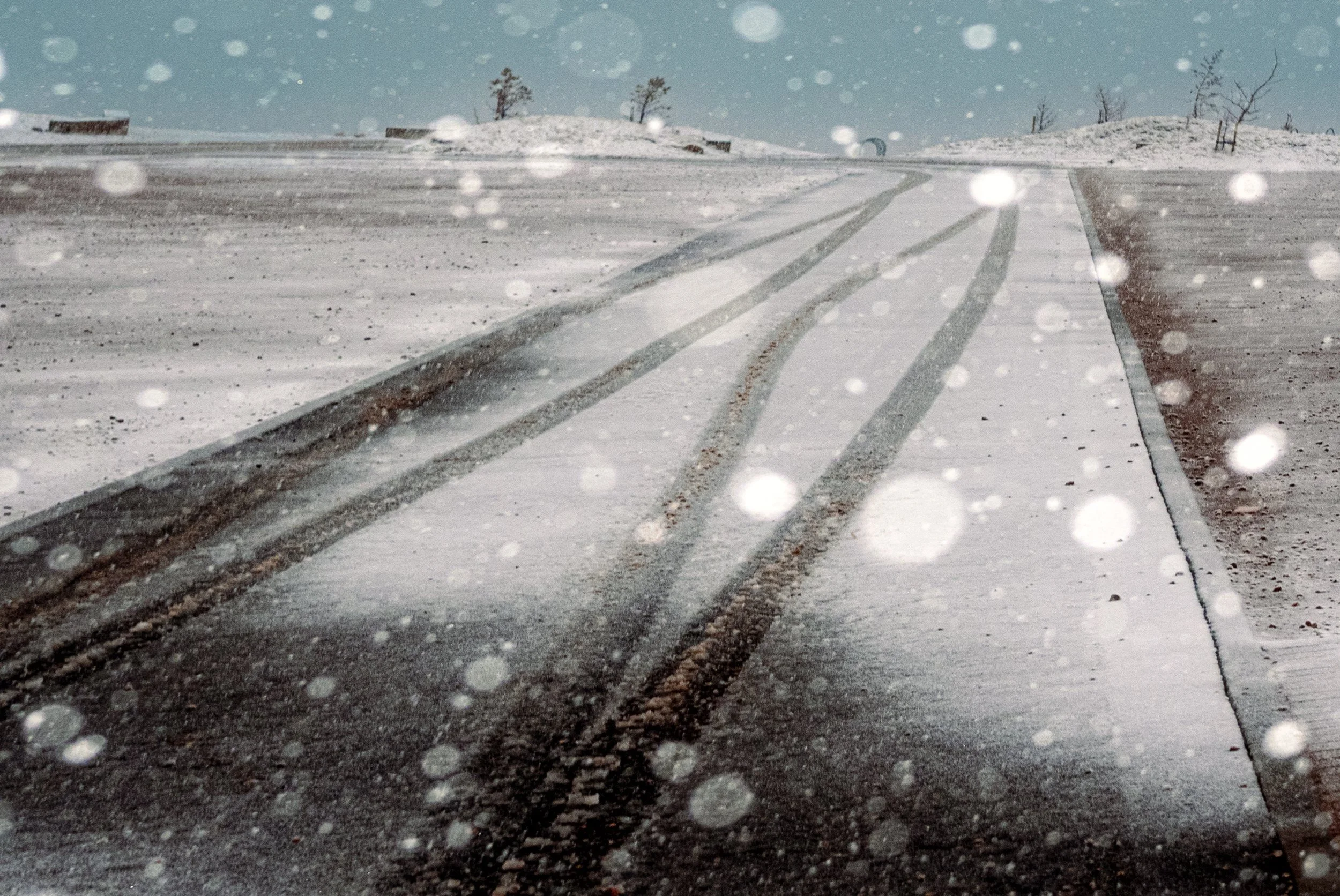 Fresh snow covers a mountain road marked by vehicle tracks, from Weather Permitting.