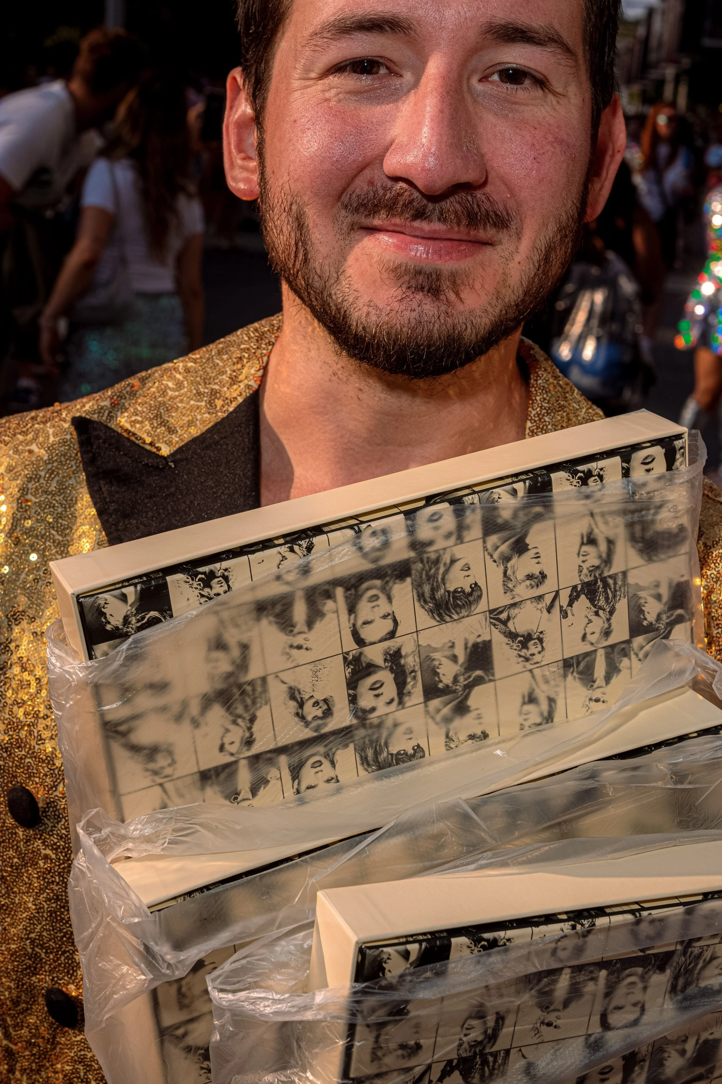 A Taylor Swift fan in a gold jacket holds up a collage of black-and-white photographs.