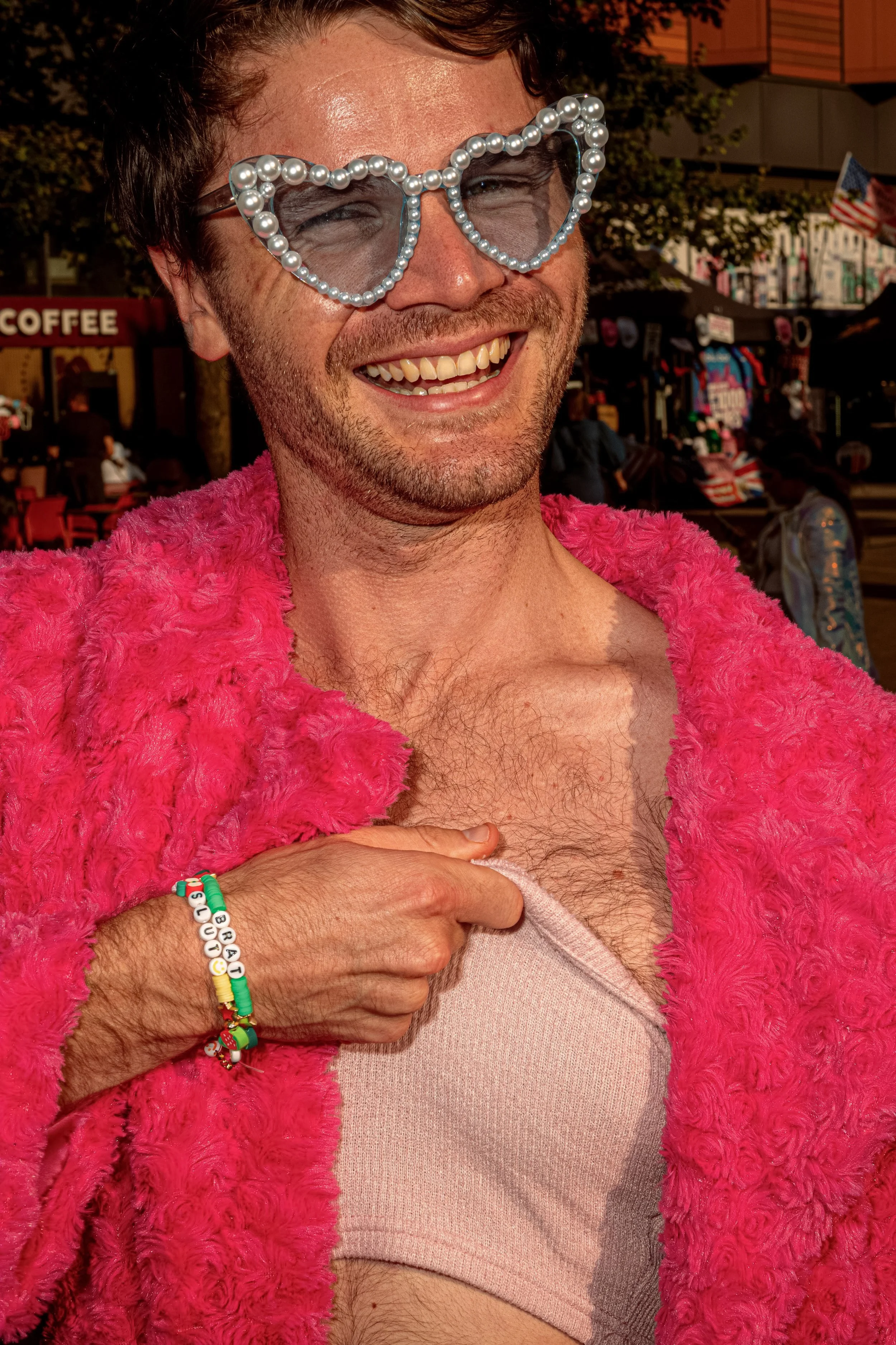 A smiling Taylor Swift fan wears sparkling heart-shaped sunglasses and a bright pink feather boa.