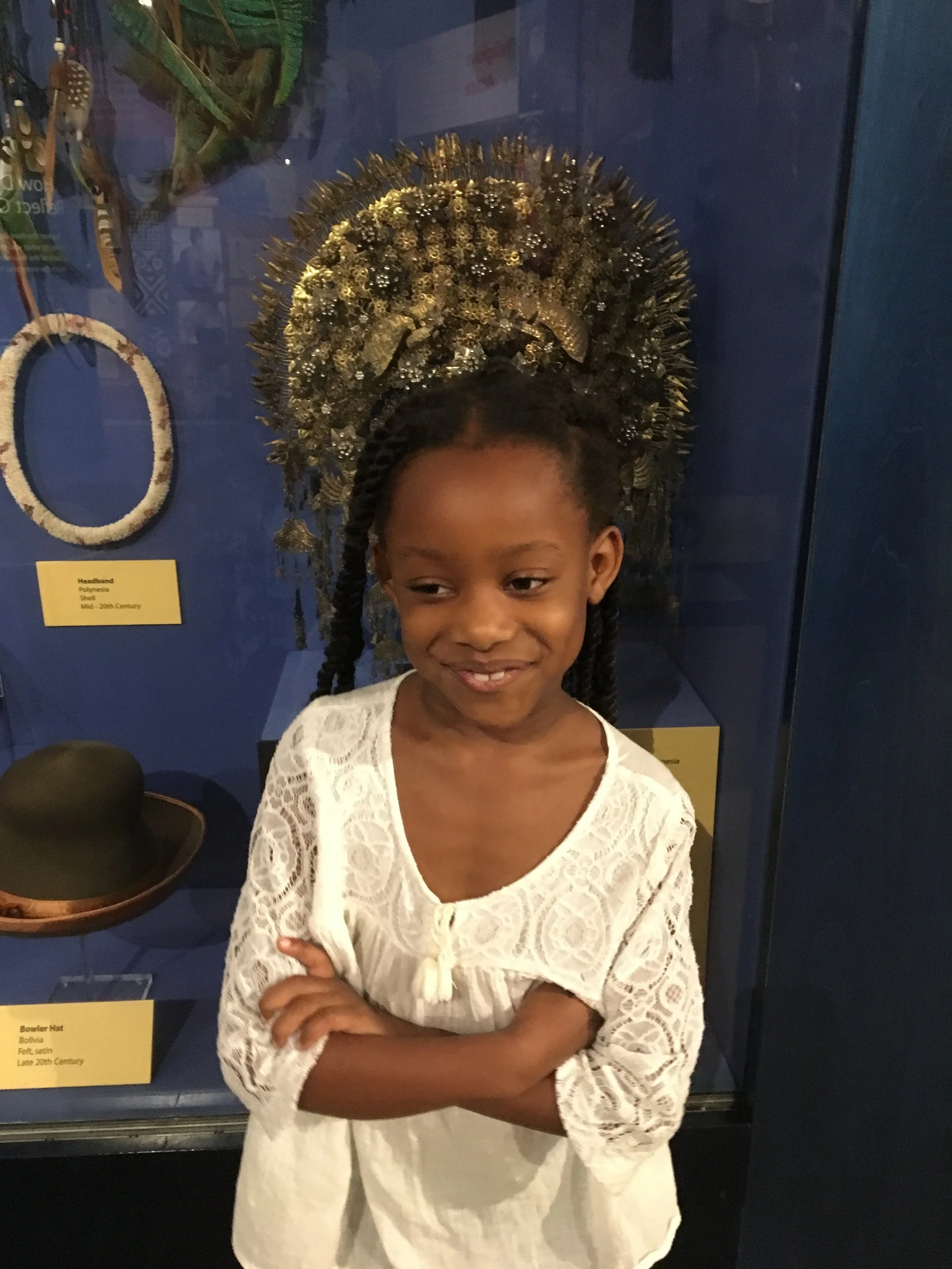 Azariah in front of one of the many opulent headpieces on display in the Reflections of Culture exhibit. 