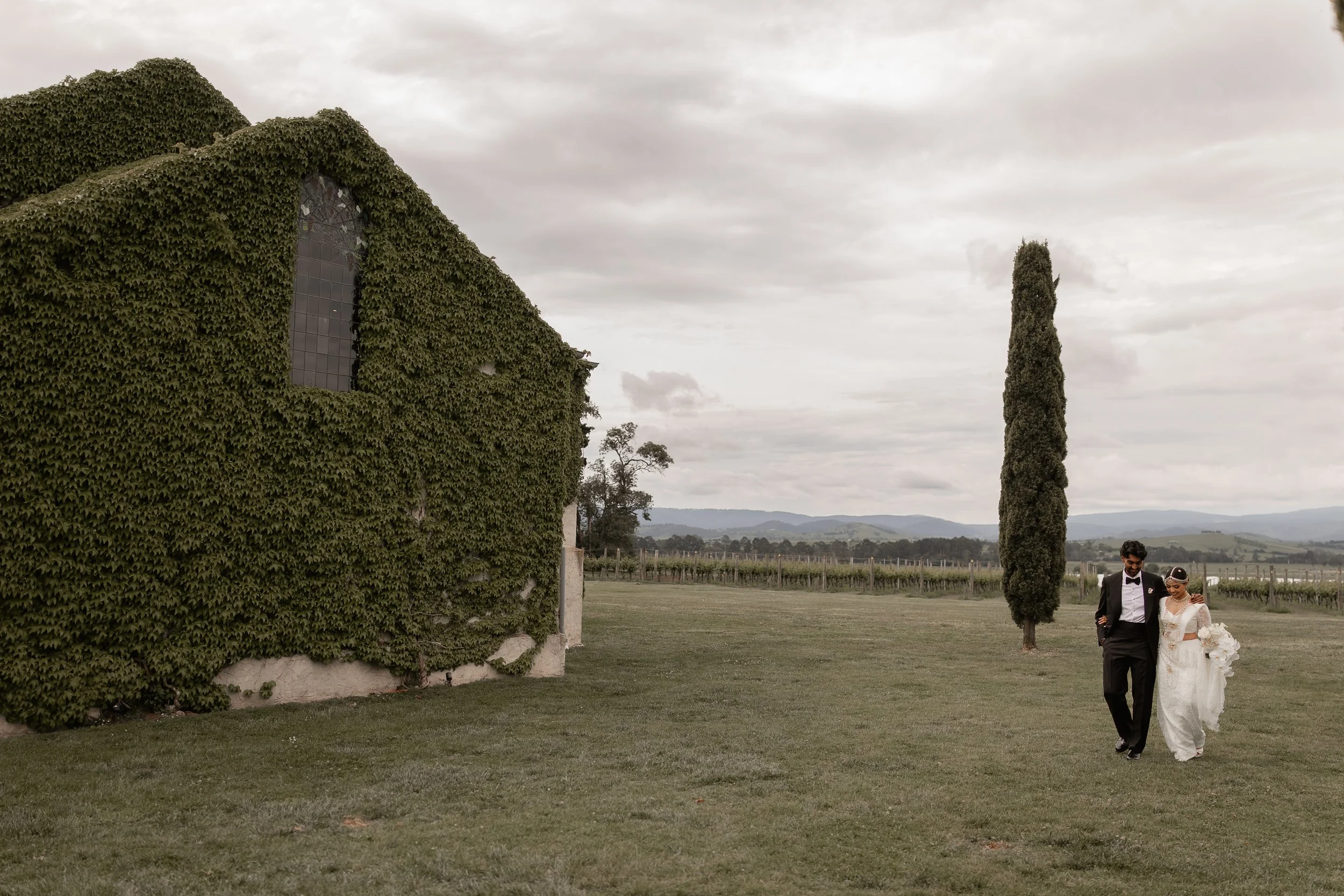 Vidura and Sanduni walking beside The Chapel at Stones of the Yarra Valley, Yarra Valley wedding venue, photographed by Shevan J.