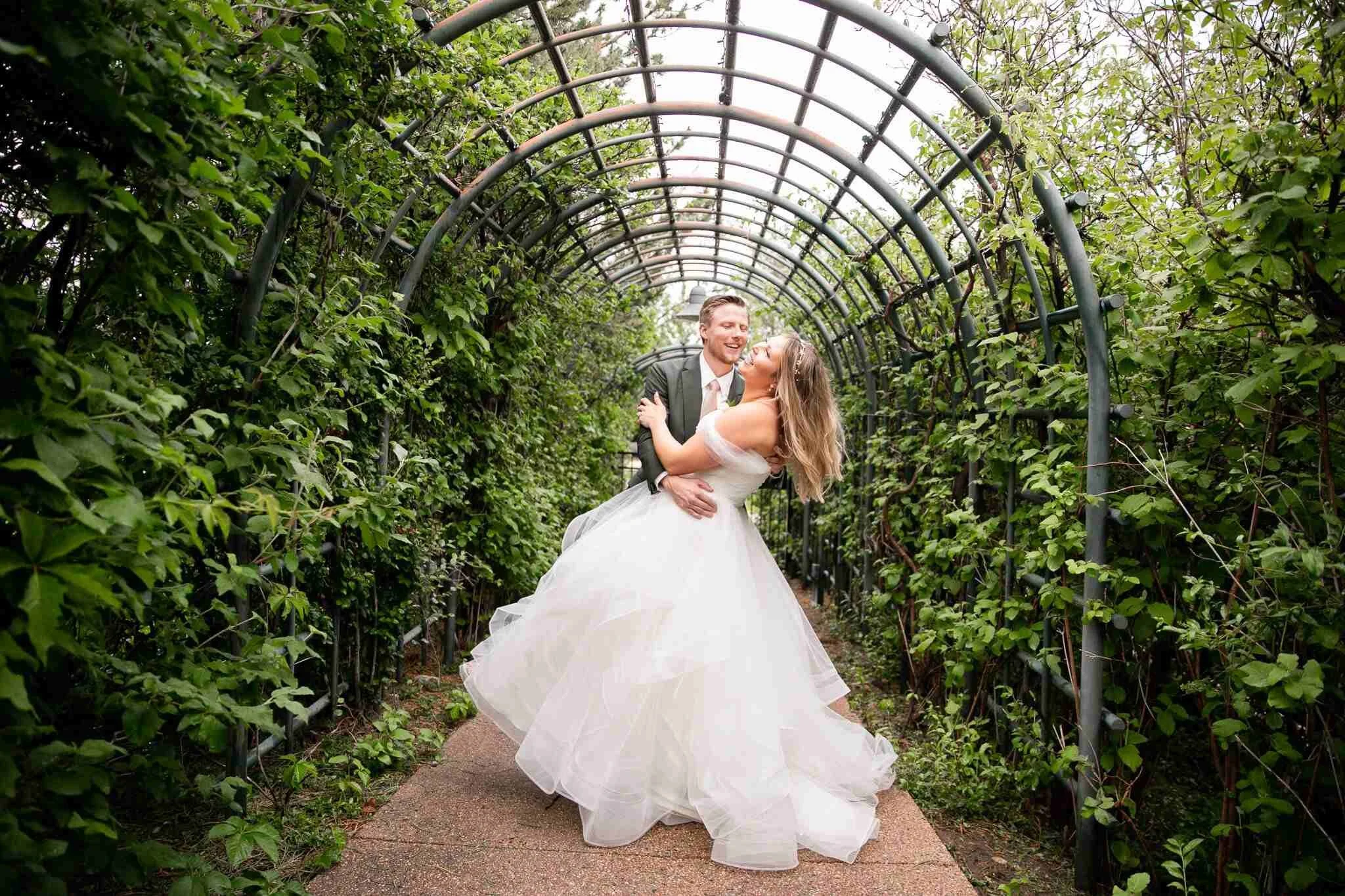 Groom dips bride inside of a greenery