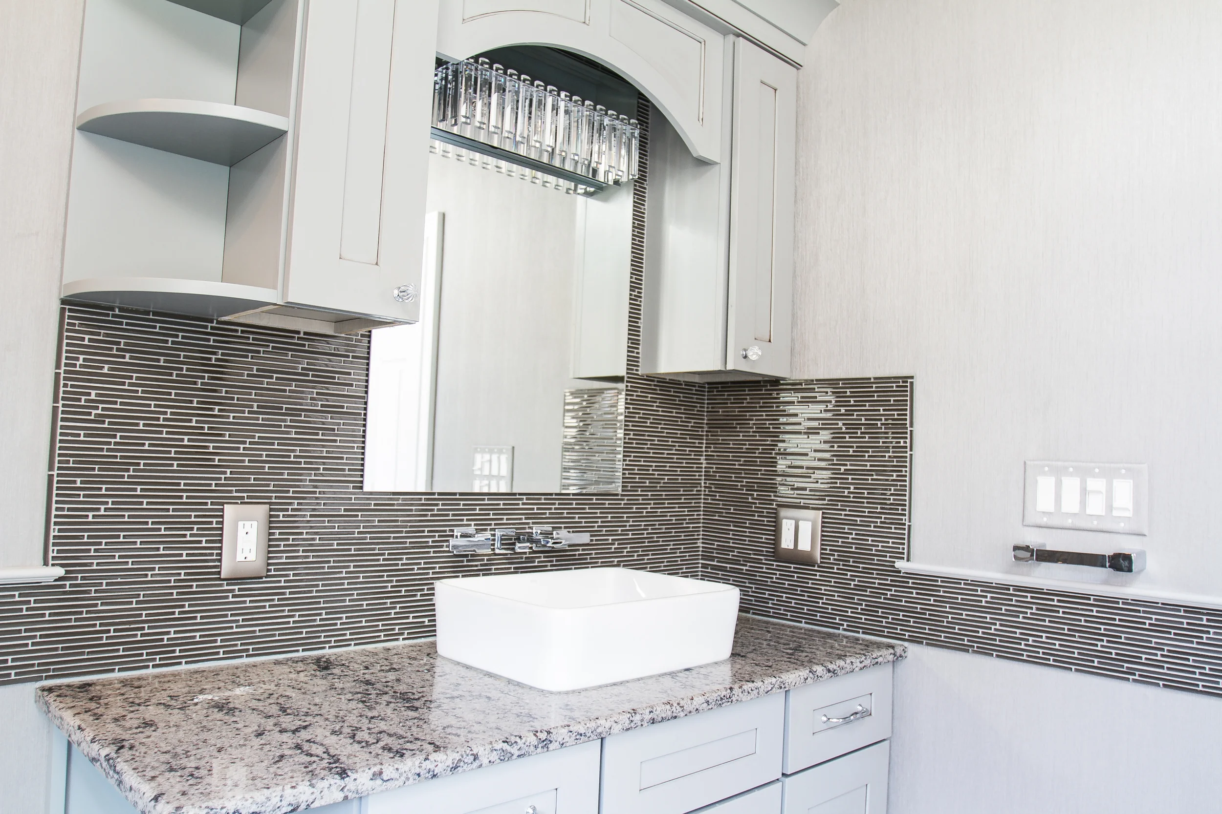A vessel bowel is added to this custom cabinet with an antique glaze. The linear tile is used on the back wall and continues around bathroom as a chair rail.