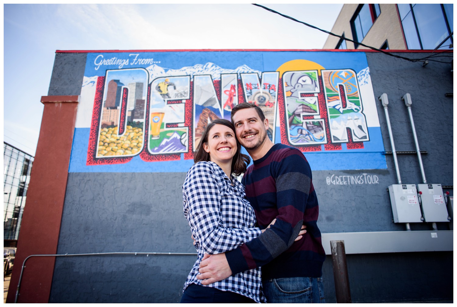 engaged couple smile in front of Denver sign