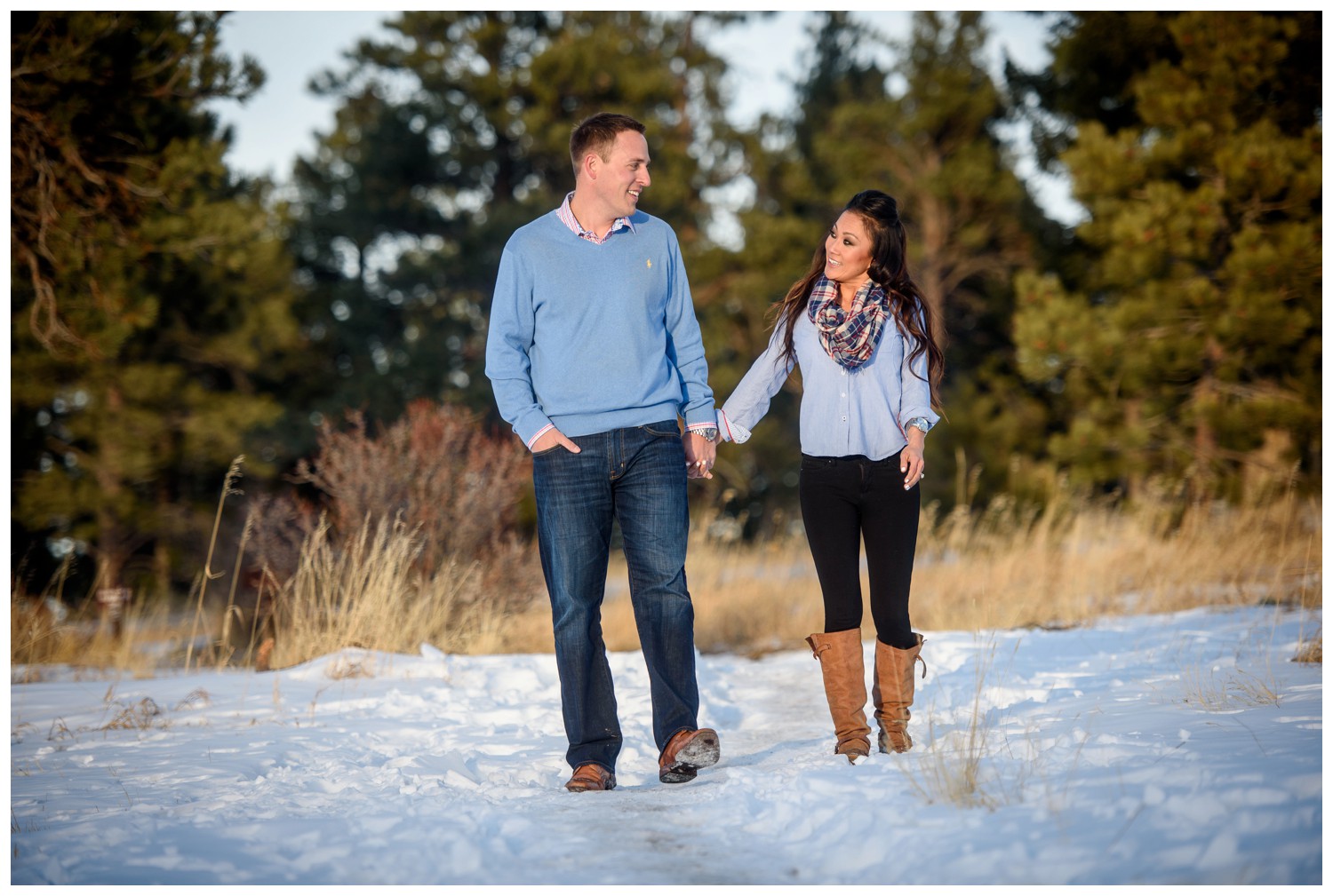 Colorado engaged couple walk through snow holding hands