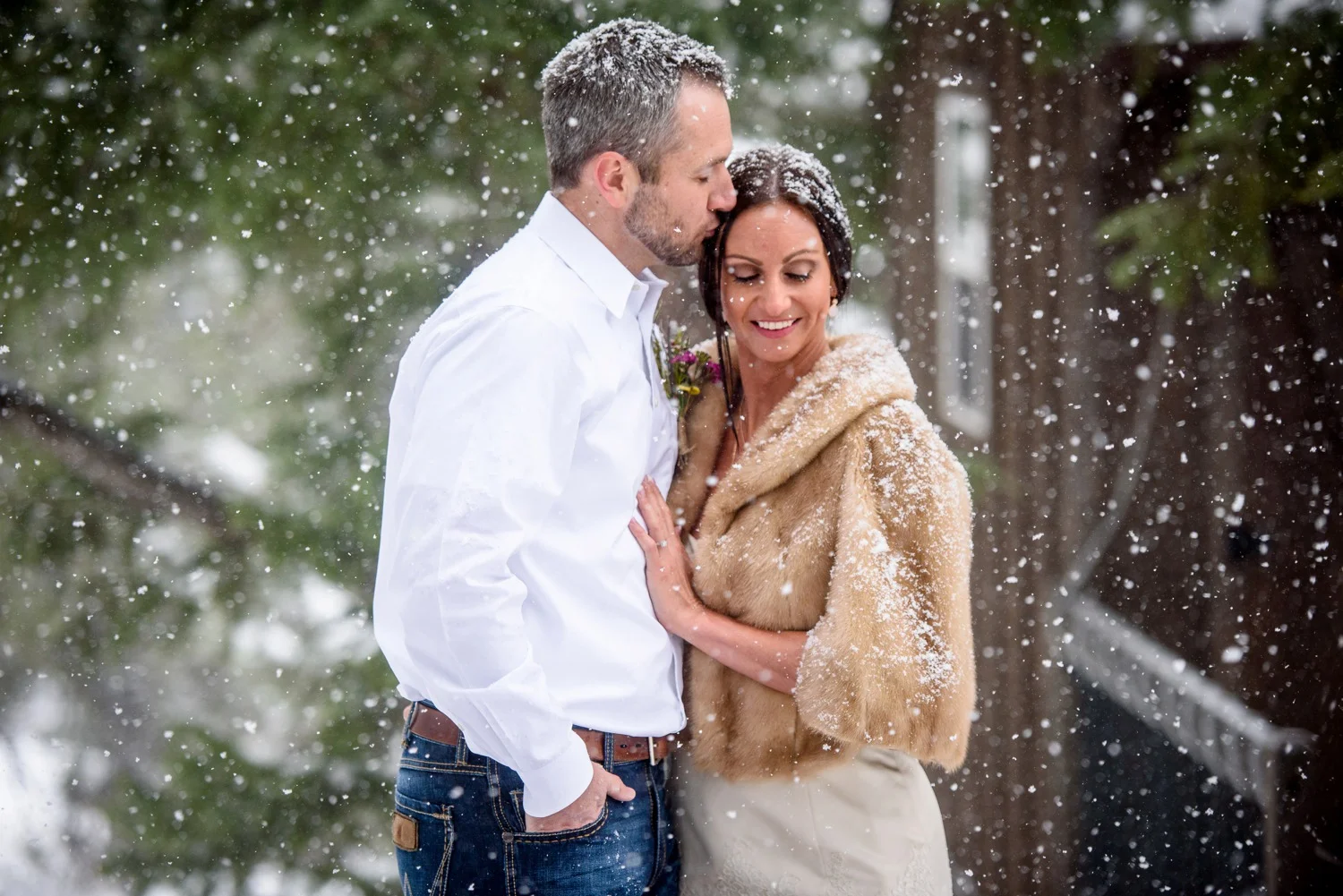 groom kisses bride in falling snow