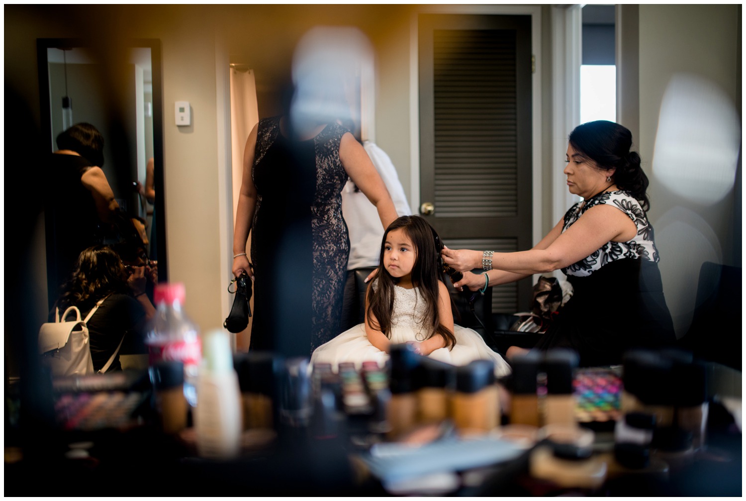 cute flower girl getting hair done in hotel room