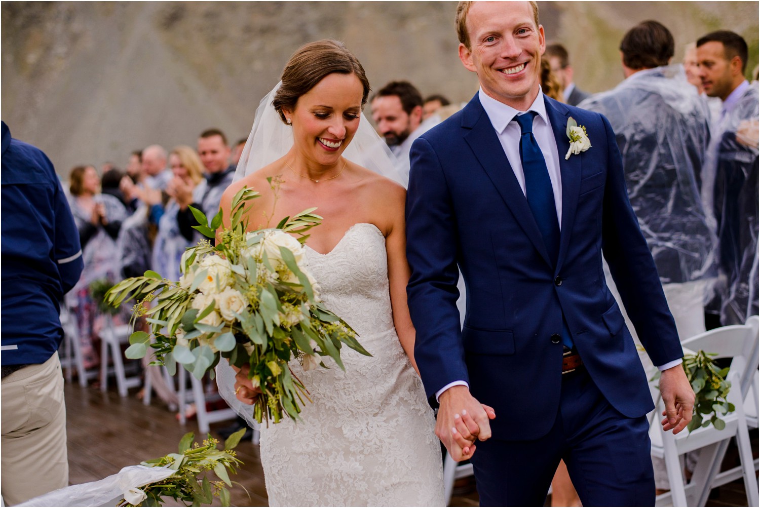 happy bride and groom walk down wedding aisle