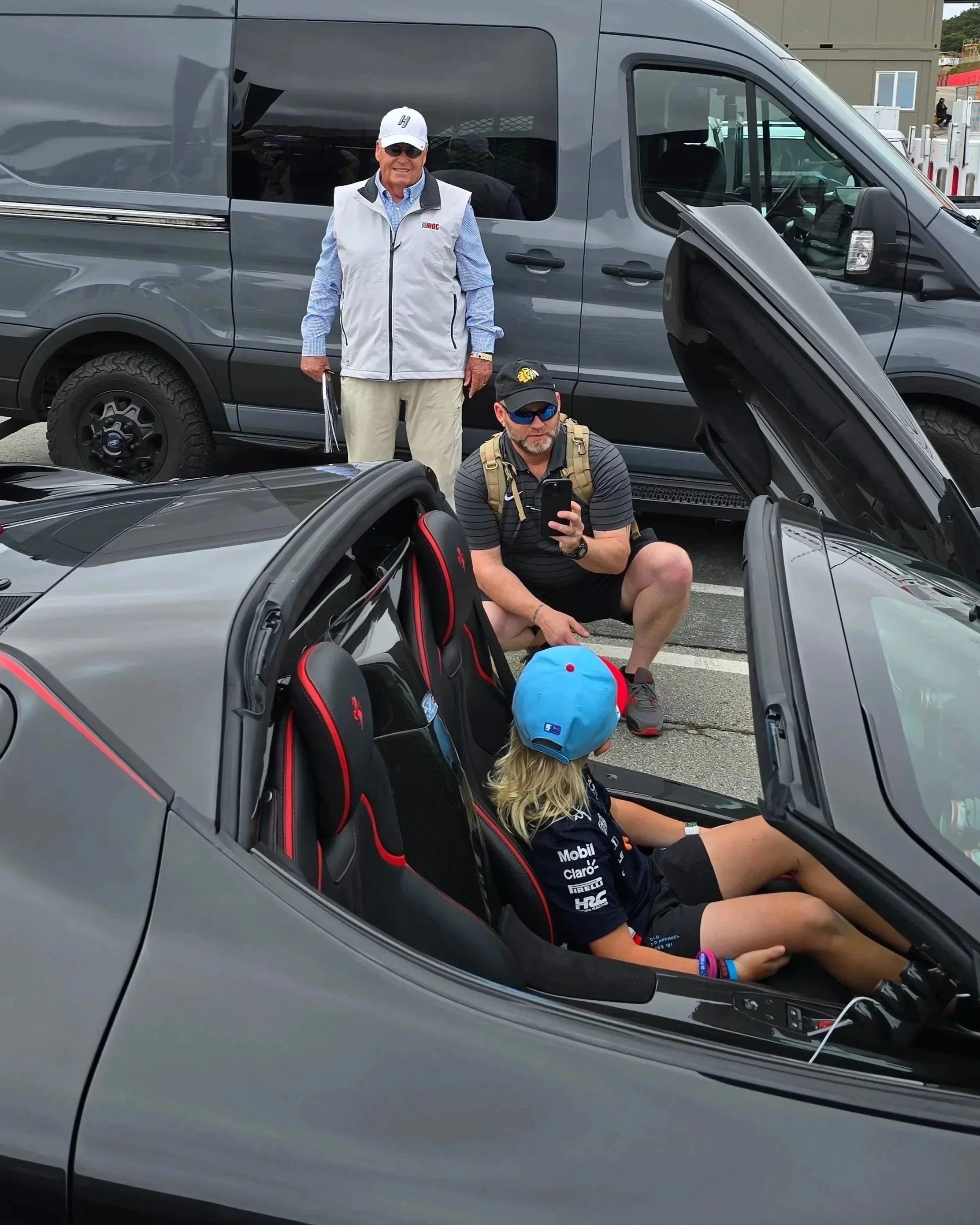 (in the vest and white hat) Owner of the Hendrick Motorsports team, Rick Hendrick, allwoing a lucky youth to sit in his jaw-dropping La Ferrari Aperta