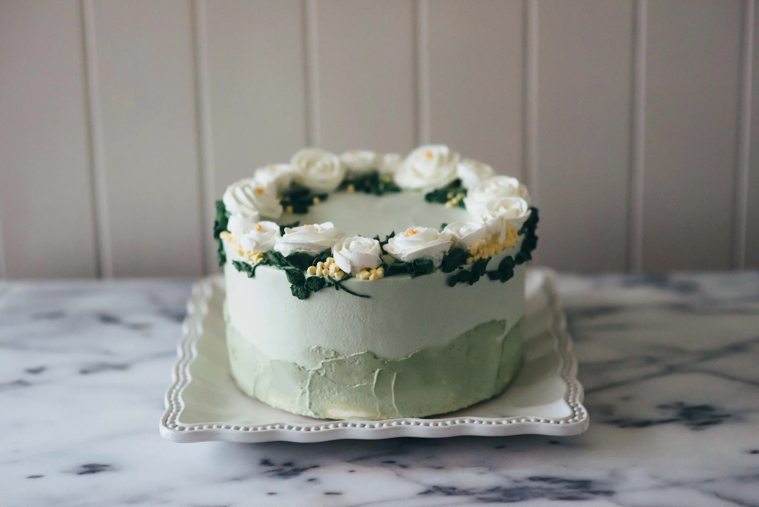 Piped wild roses with dainty leaves creating a crown on the cake
