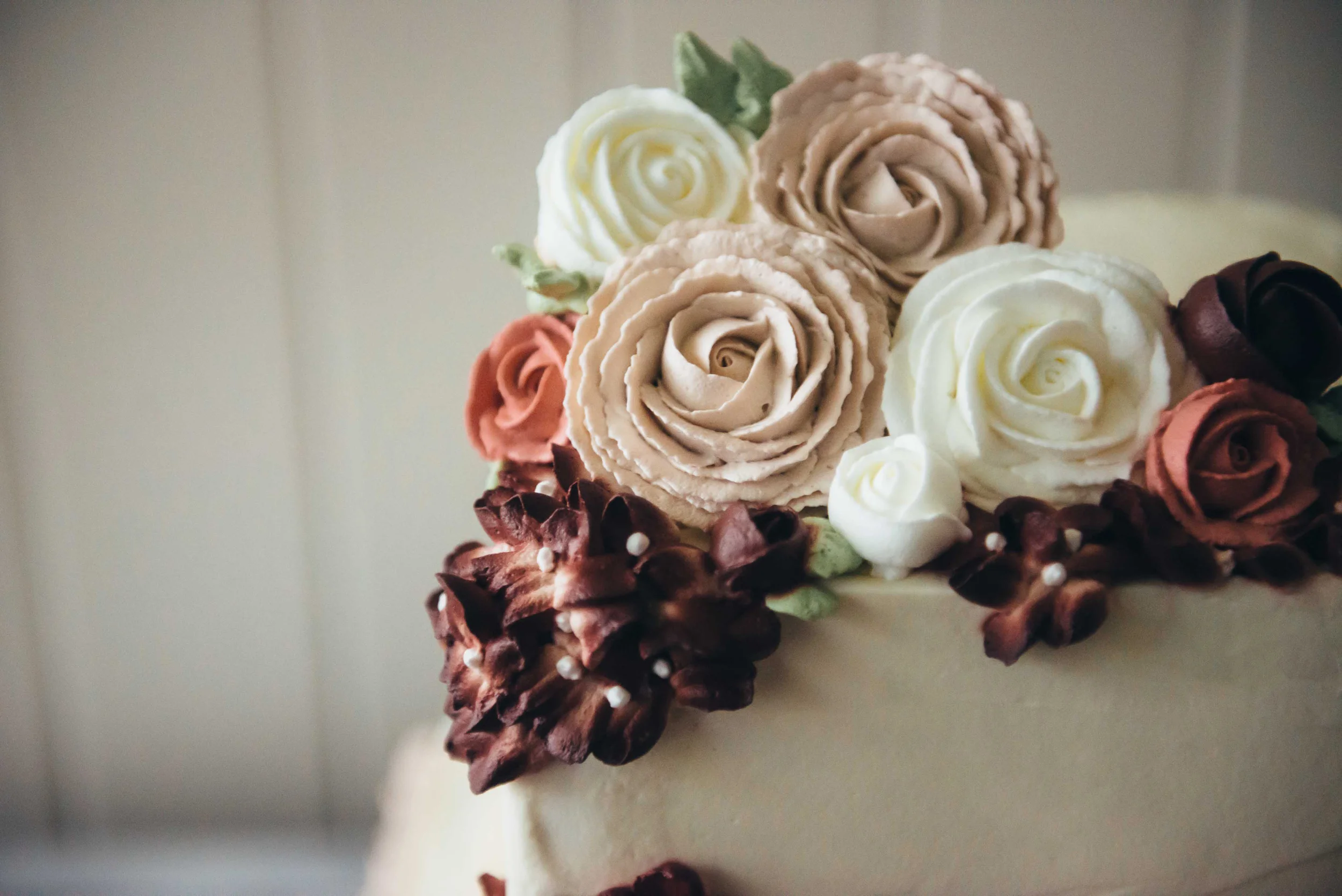 Three layers of mocha kahlua cake with dusty pink ruffles on the base and groups of cascading roses and hydrangeas