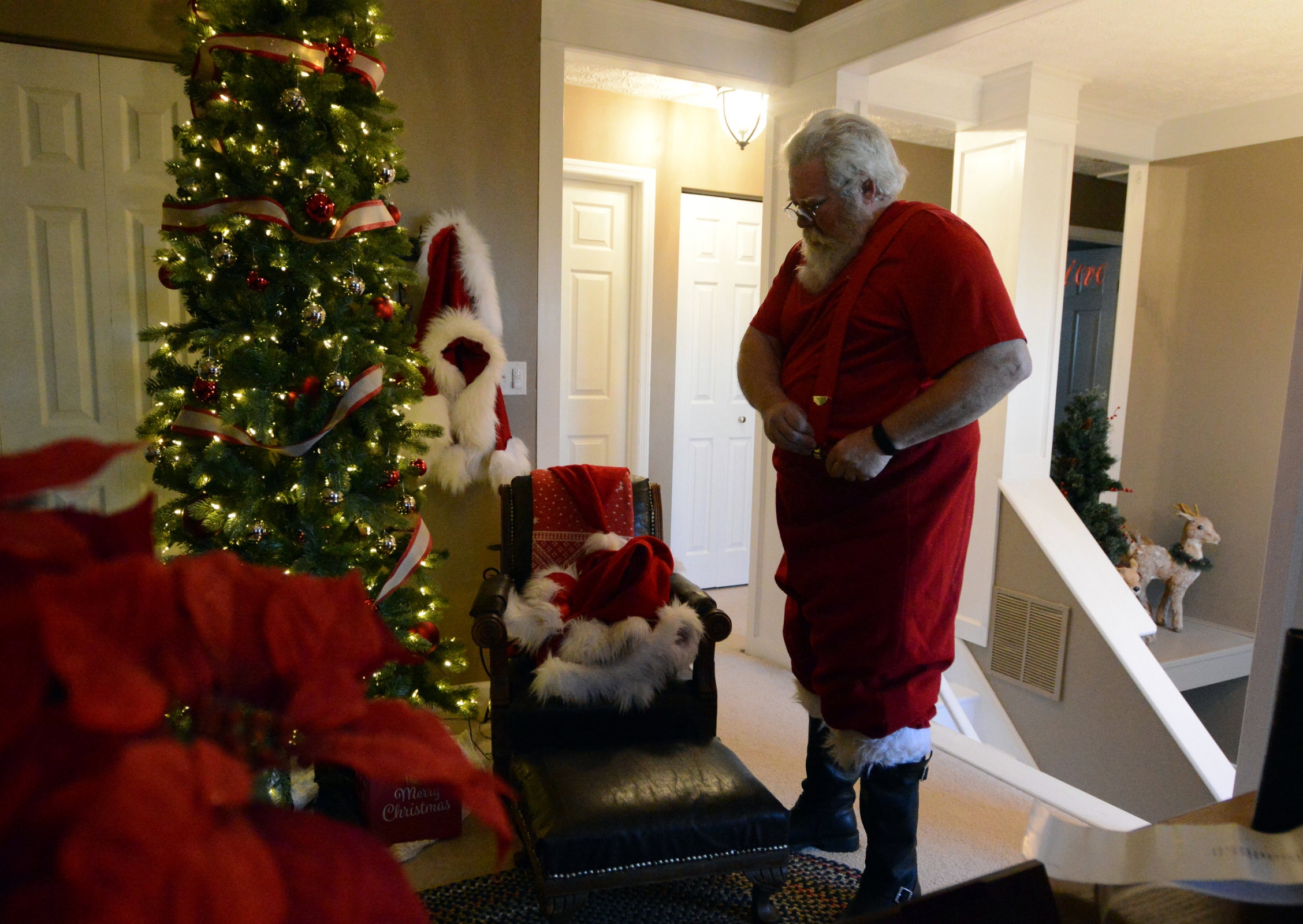 Tim Etienne puts on his suspenders as he dresses in his traditional Santa Claus suit Friday evening, Dec. 1, 2017, at his home in Canal Winchester. 