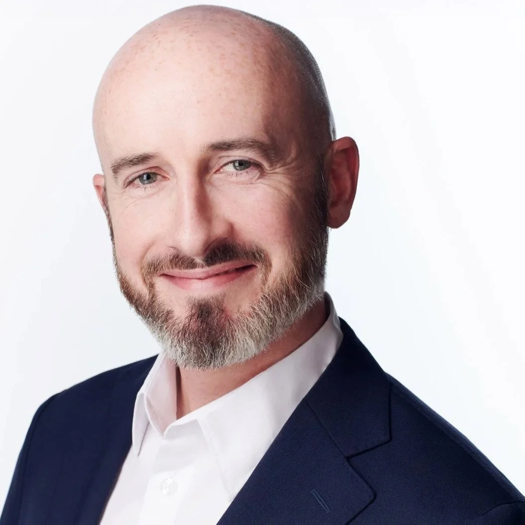 Smiling person with curly hair and glasses