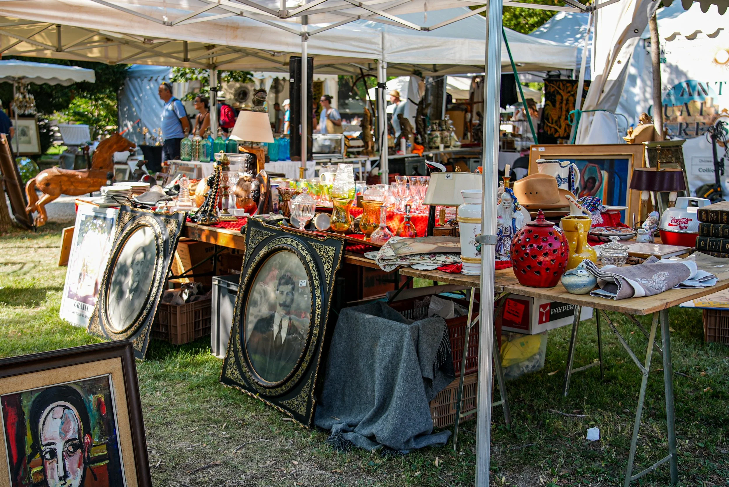 Antique portraits and glassware under market tents
