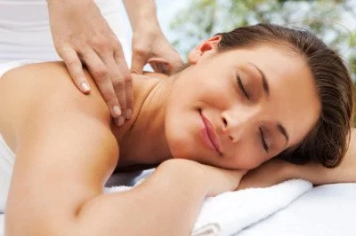 Woman receiving a back massage while lying face down with eyes closed.