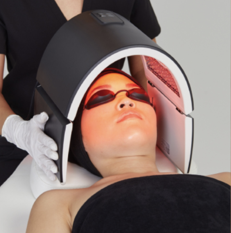 Person undergoing LED light therapy treatment on face using a specialized mask.