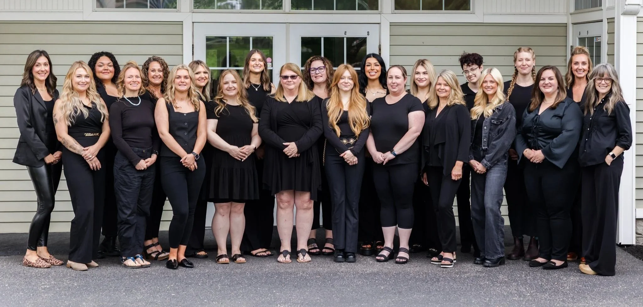 Group of women standing outside in front of a building, all dressed in black.