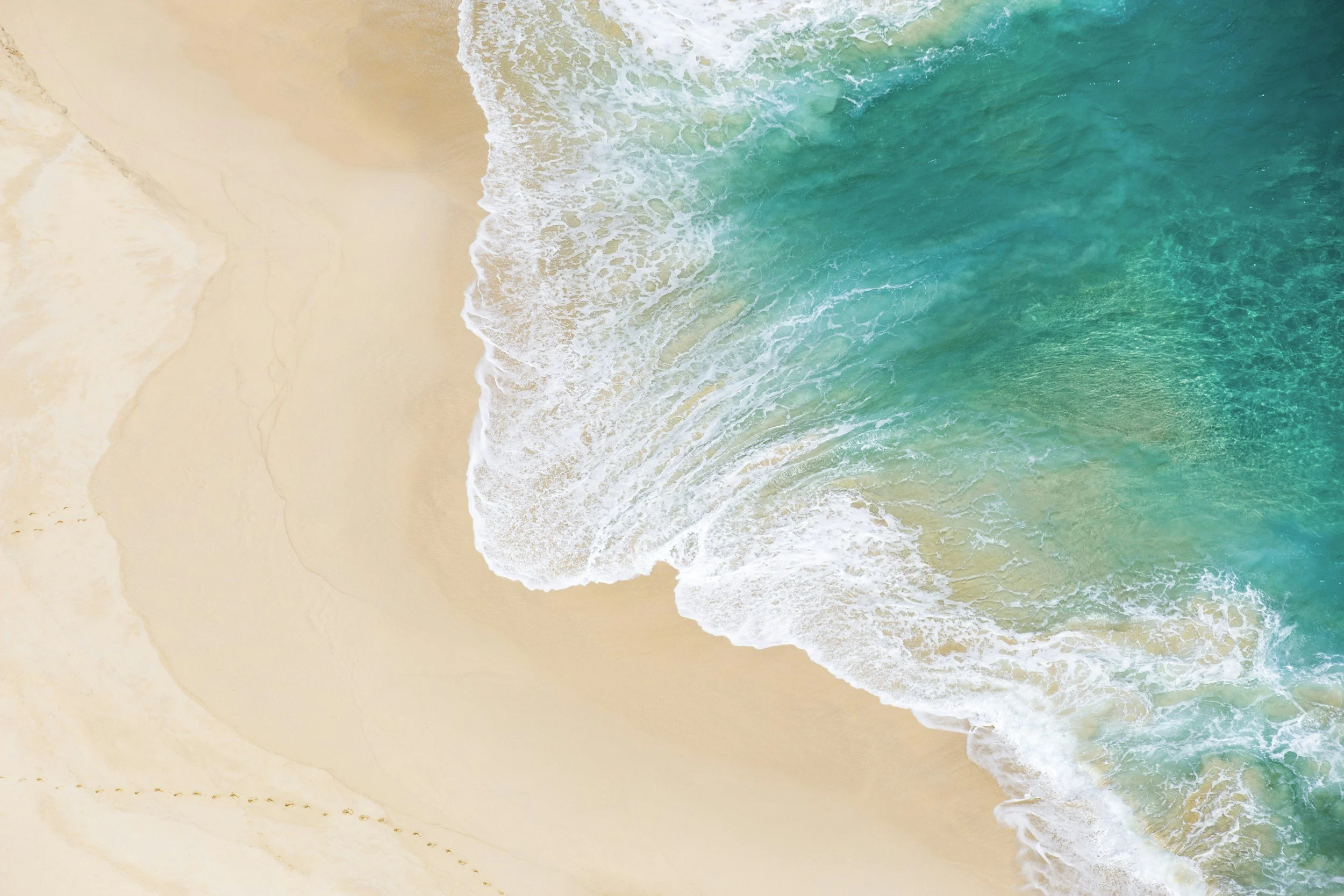 Image of the teal blue ocean meeting the beach - which feels calm and serene