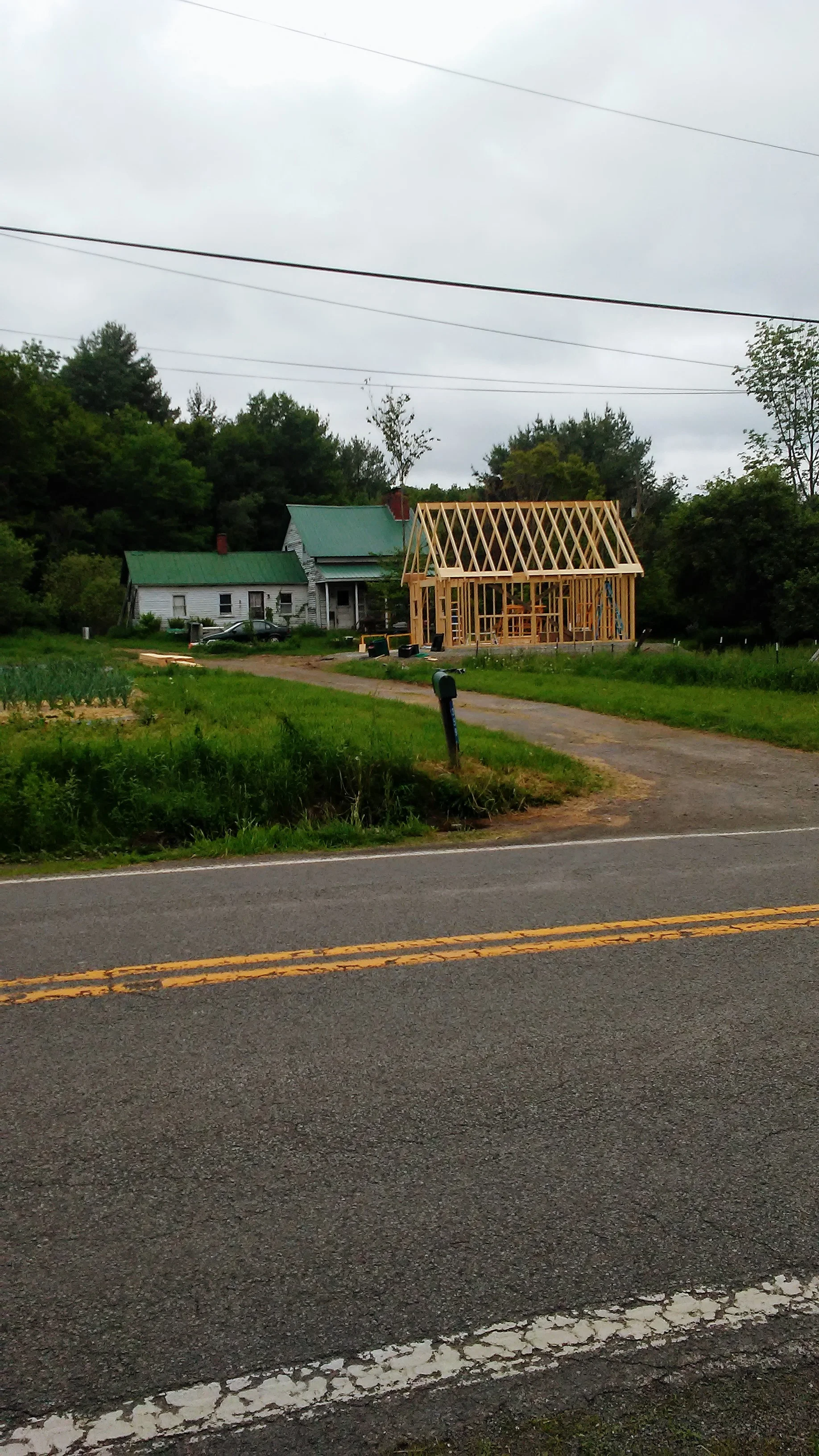 Here’s the view from across the road, with Milt’s house in the background. The ability to store vegetables in the walk-in and prep for market under a roof on rainy days makes us farmers jump for joy!