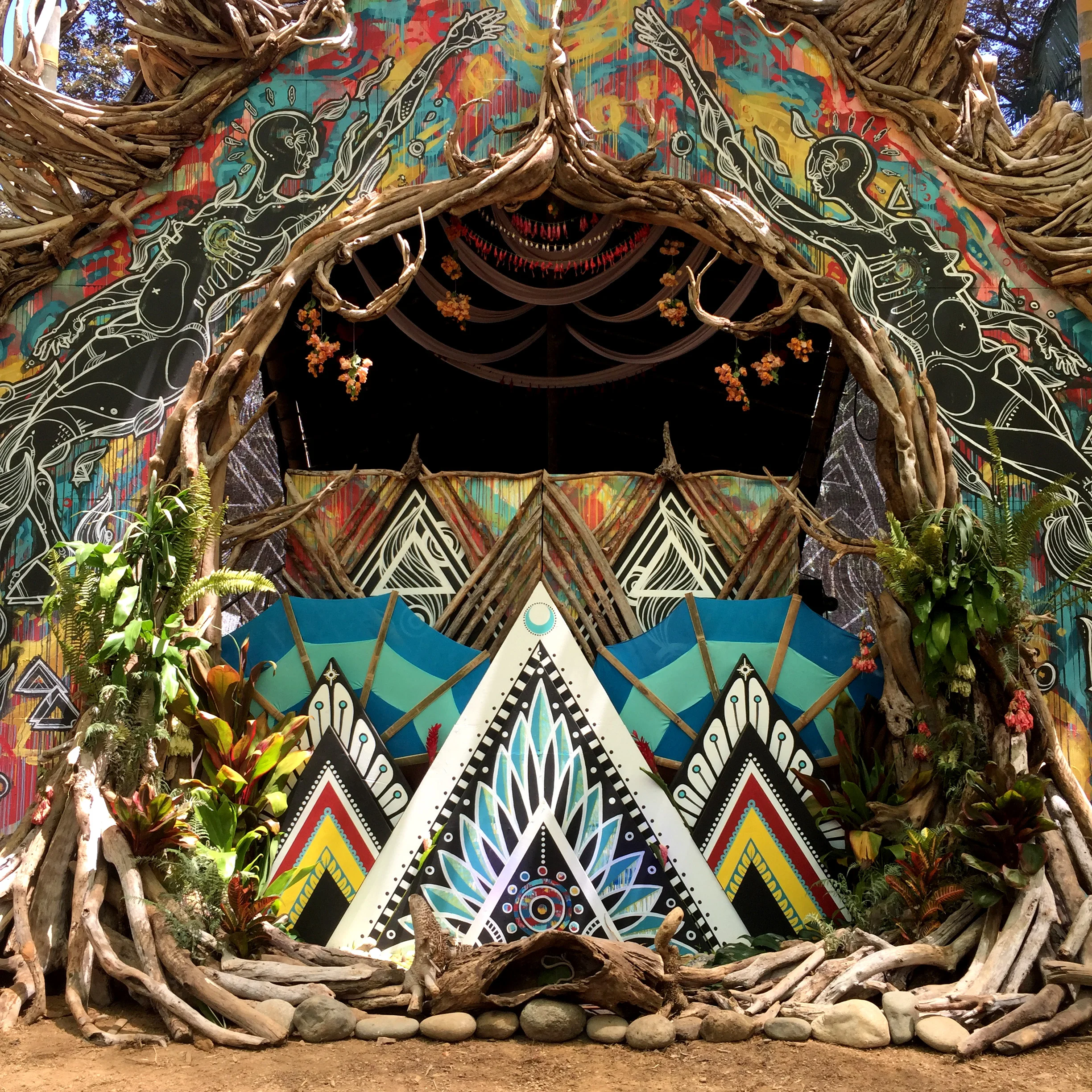 mural + driftwood sculpture by Tigre Bailando, with Andria Dawn fabric drape by Jacob Troy dj table facade by Abbie Gribsgov + Sunny Ochala. bamboo fans designed and built by Smiley Rendon altar triangles painted by Andria Dawn.