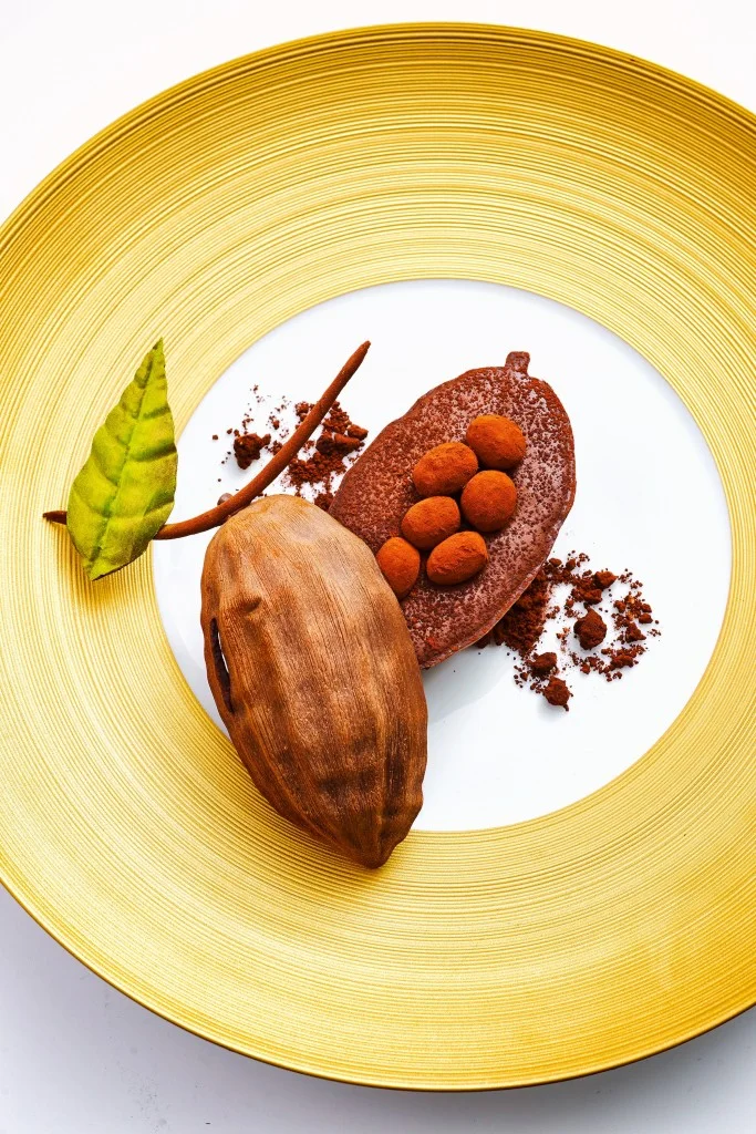 圖8. 巴黎五星級飯店 Le Bristol 前甜點主廚 Laurent Jeannin 的招牌甜點之一「Chocolat du Pérou」(秘魯巧克力)。他在盤子上用不同的甜點元素、口味與質地再現了巧克力豆的真實樣貌。注意盤子的選擇,不管是顏色還是設計都與甜點整體協調搭配、也完美地烘托了主題。(圖片來源: L’Express Styles )