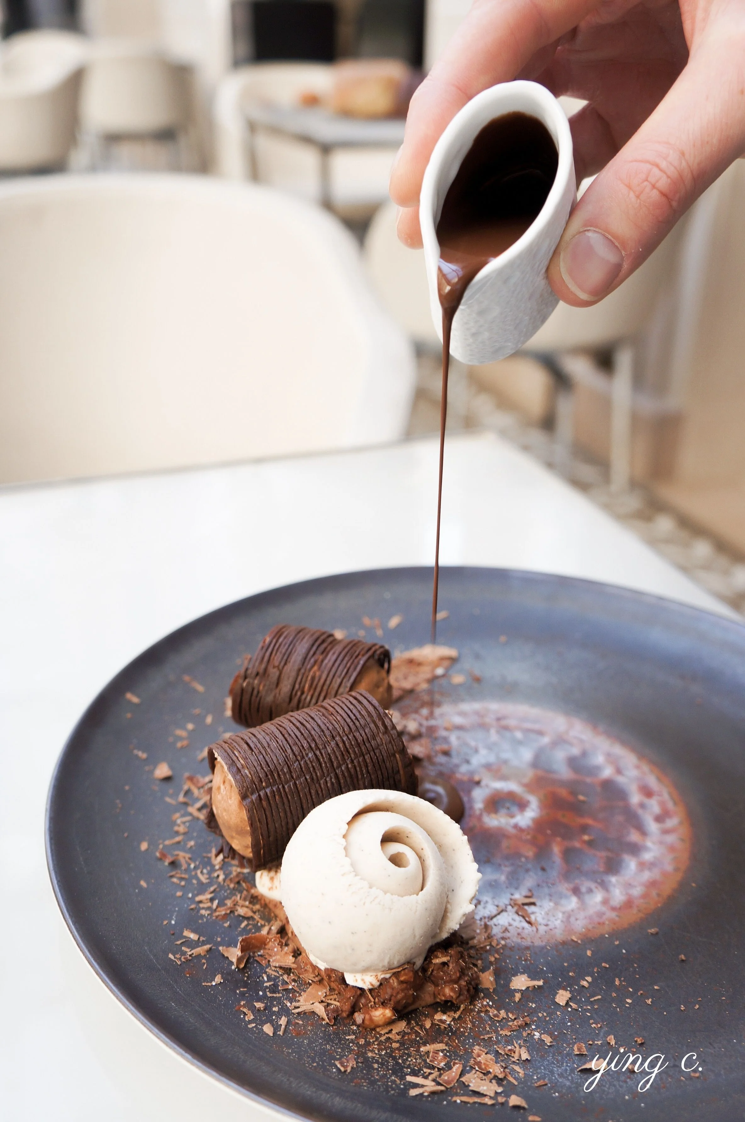 l’Orangerie 餐廳的「 Fines feuilles & soufflé, chocolat noir, cardamome 」(黑巧克力薄片與舒芙蕾、小荳蔻)盤式甜點。享用之前,侍者會在顧客面前將巧克力醬緩緩注入盤中。