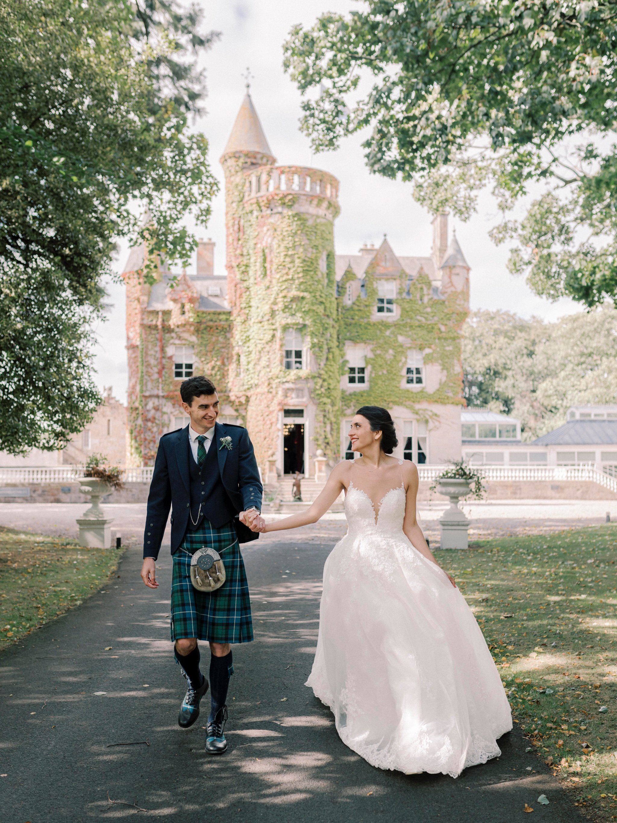 20_carlowrie castle edinburgh wedding photographer bride and groom walking away from castle.jpg