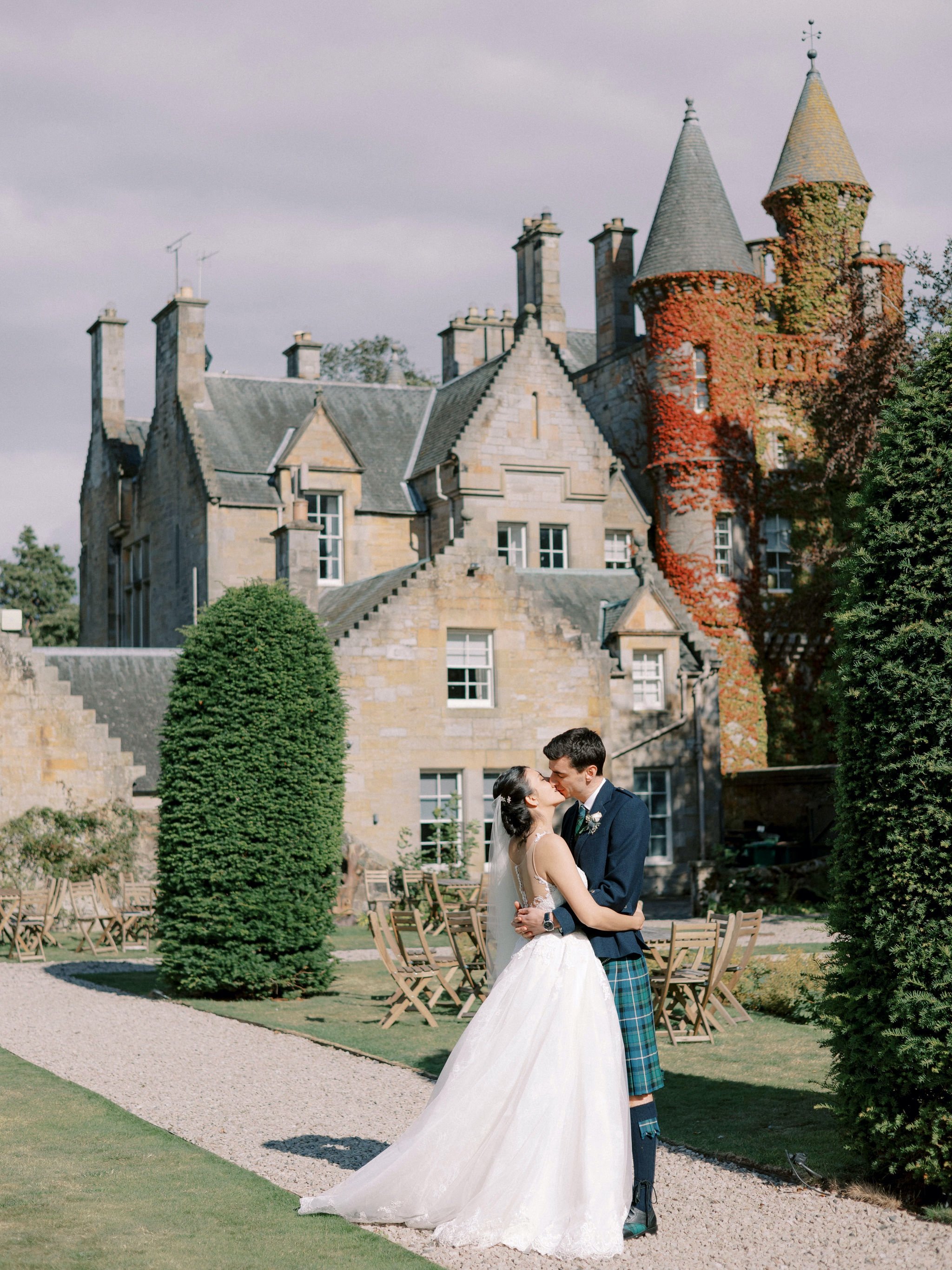 27_carlowrie castle edinburgh wedding photographer bride and groom kissing with castle in the background.jpg