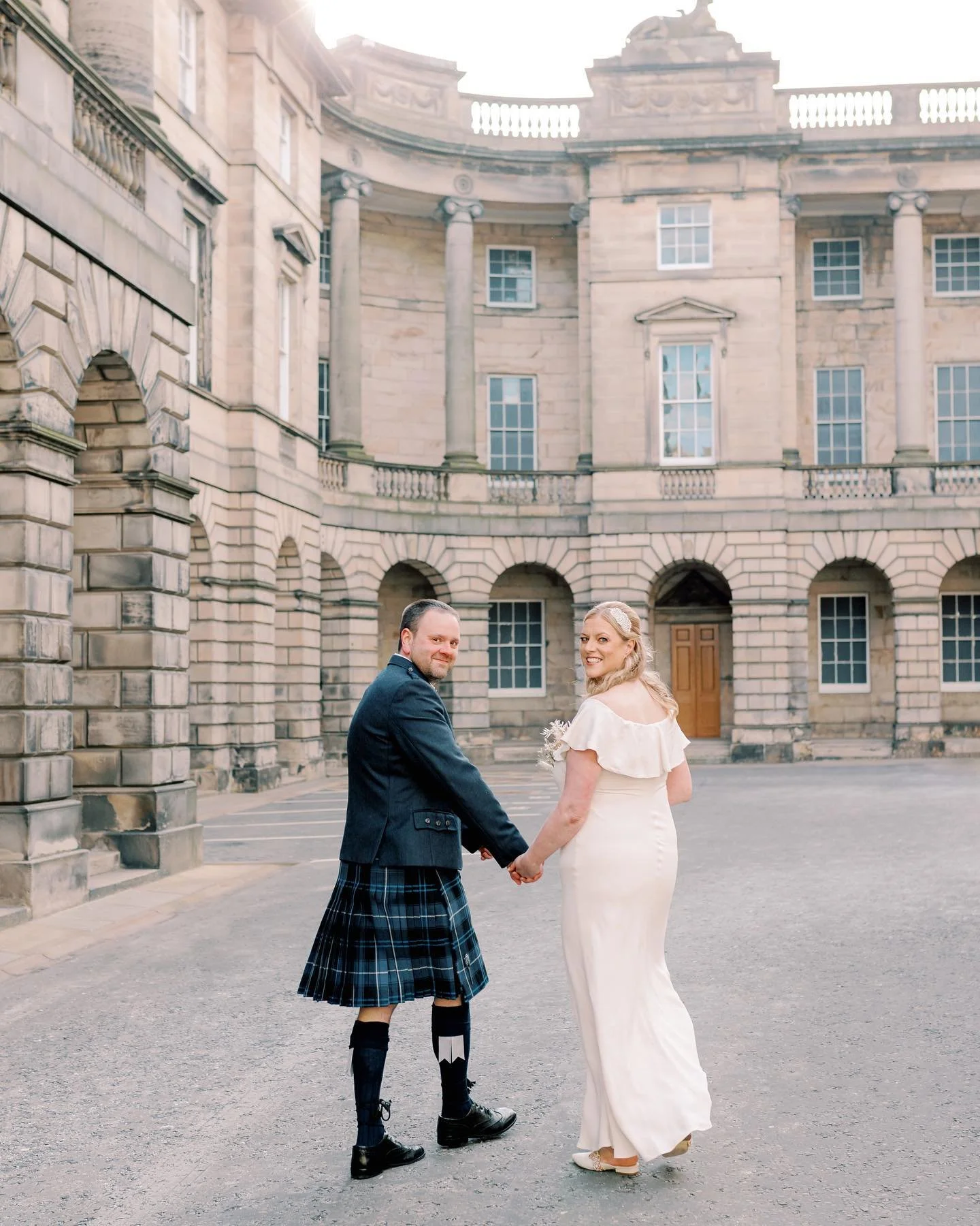 bride and groom walking through parliament square in edinburgh old town
