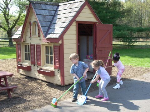 Children sweep outside a playhouse