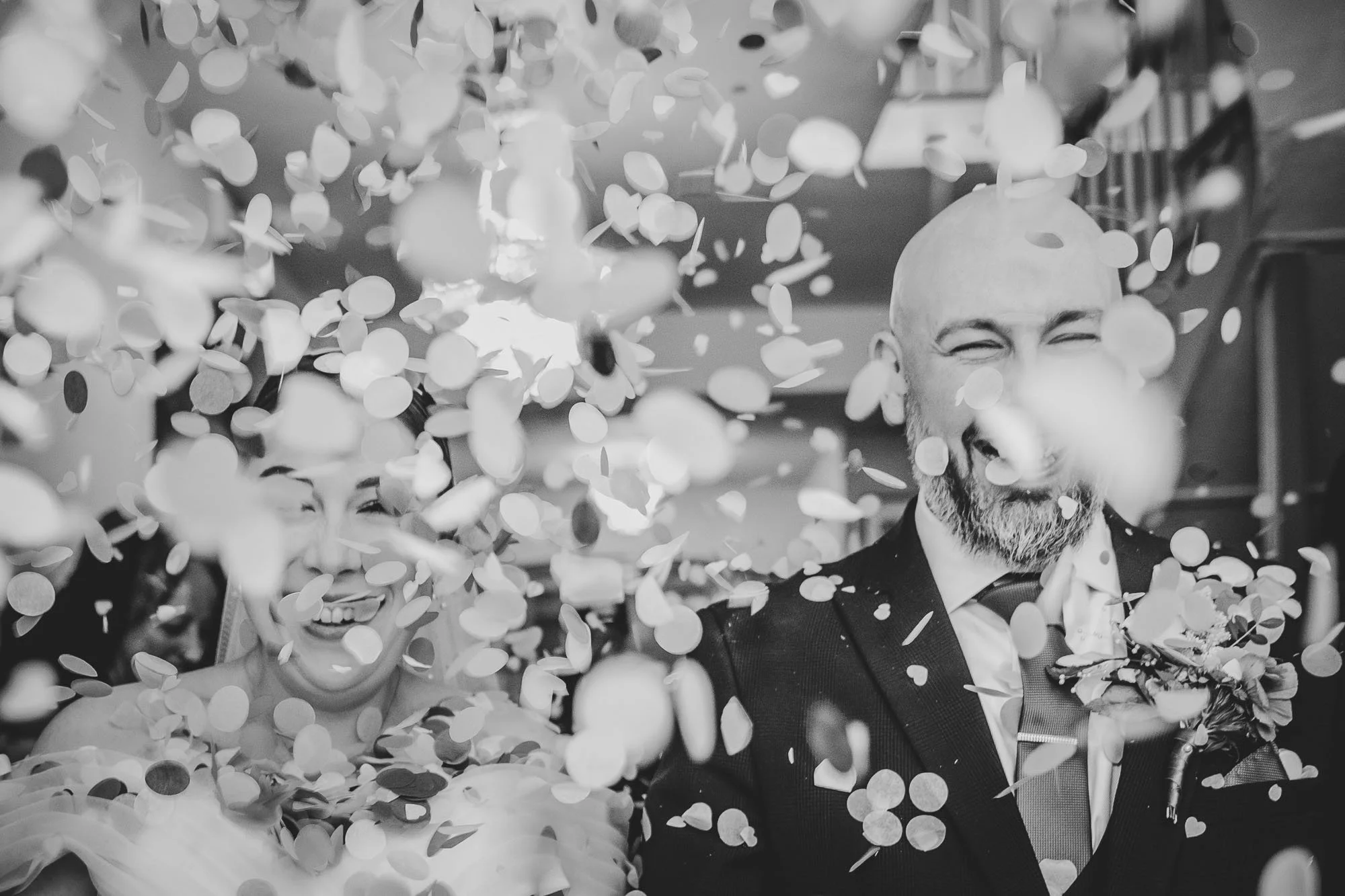 bride and groom walking through confetti laughing