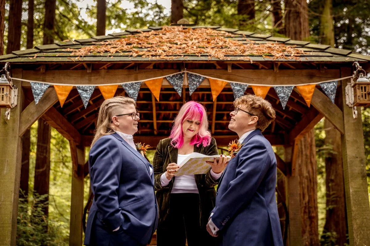 A celebrant with bright pink hair hosts an LGBT wedding ceremony in the red woods in Pulborough