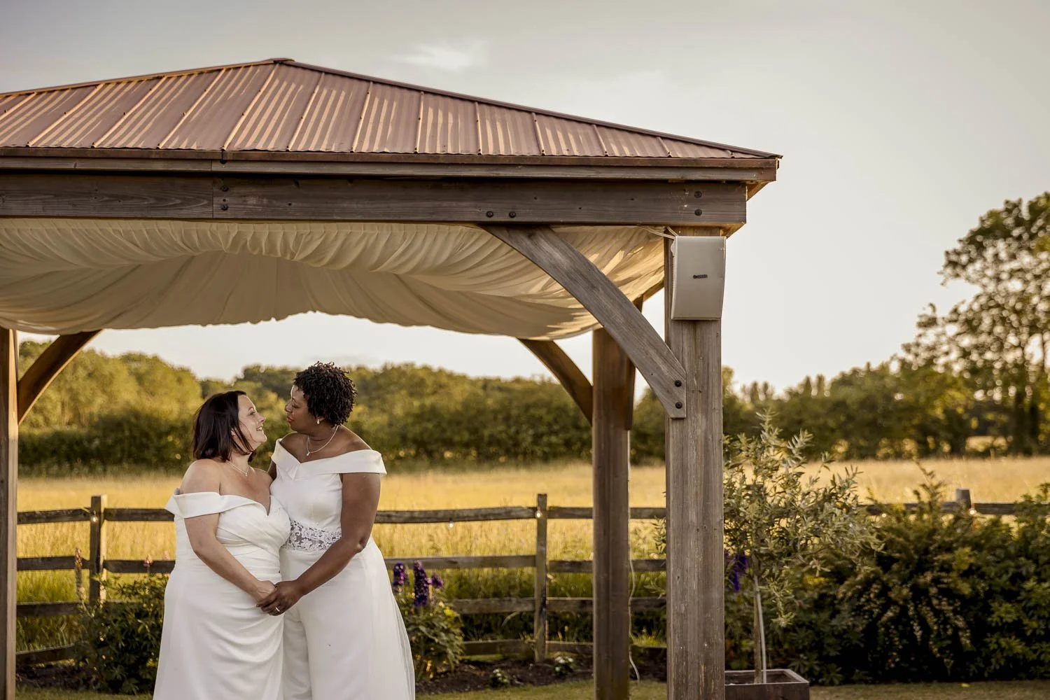 Two brides share a private moment with a countryside backdrop at their Elmshtorpe wedding venue Badgers Mount Hotel in Leicestershire